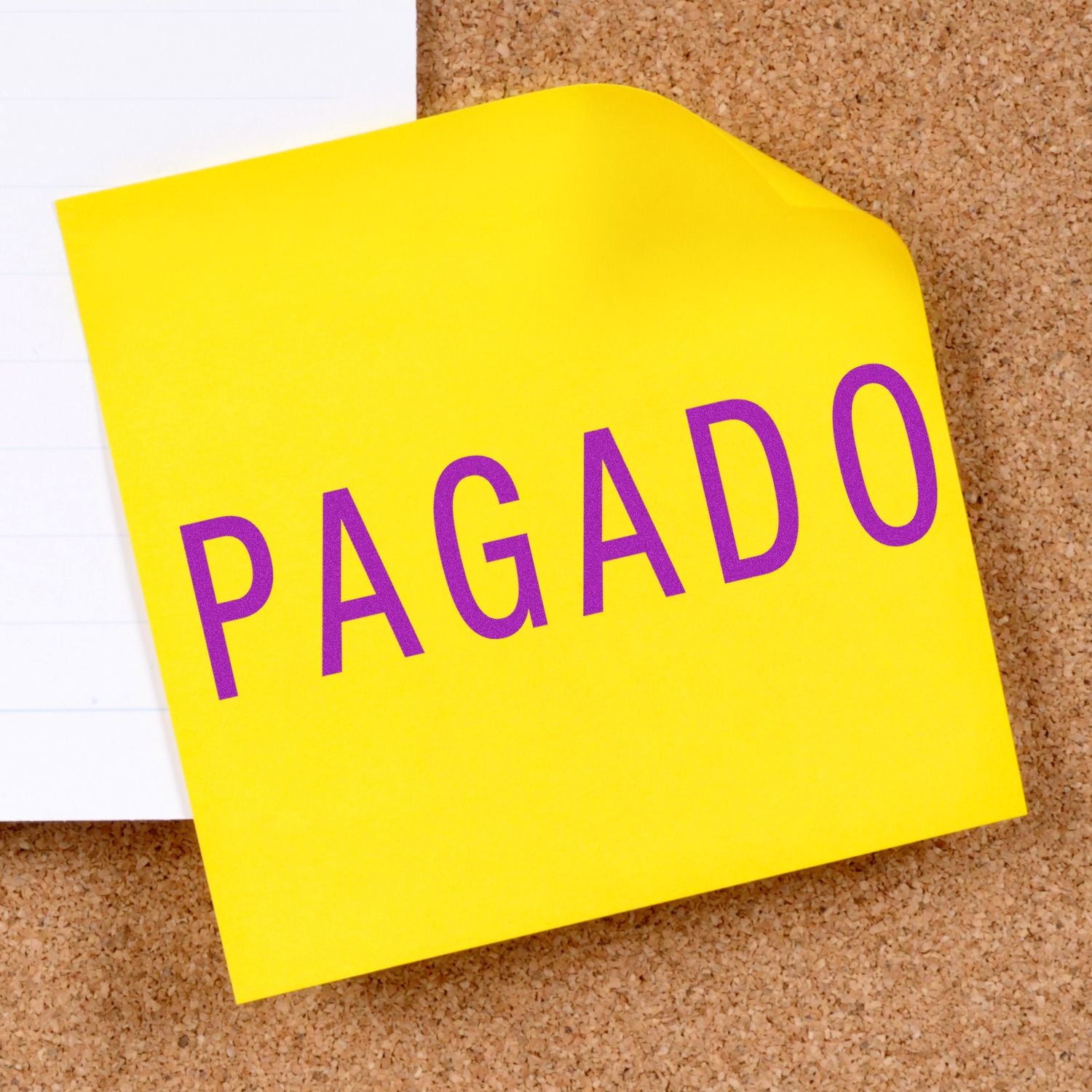 Yellow sticky note with "PAGADO" stamped in purple ink using the Pagado Rubber Stamp, pinned on a corkboard.