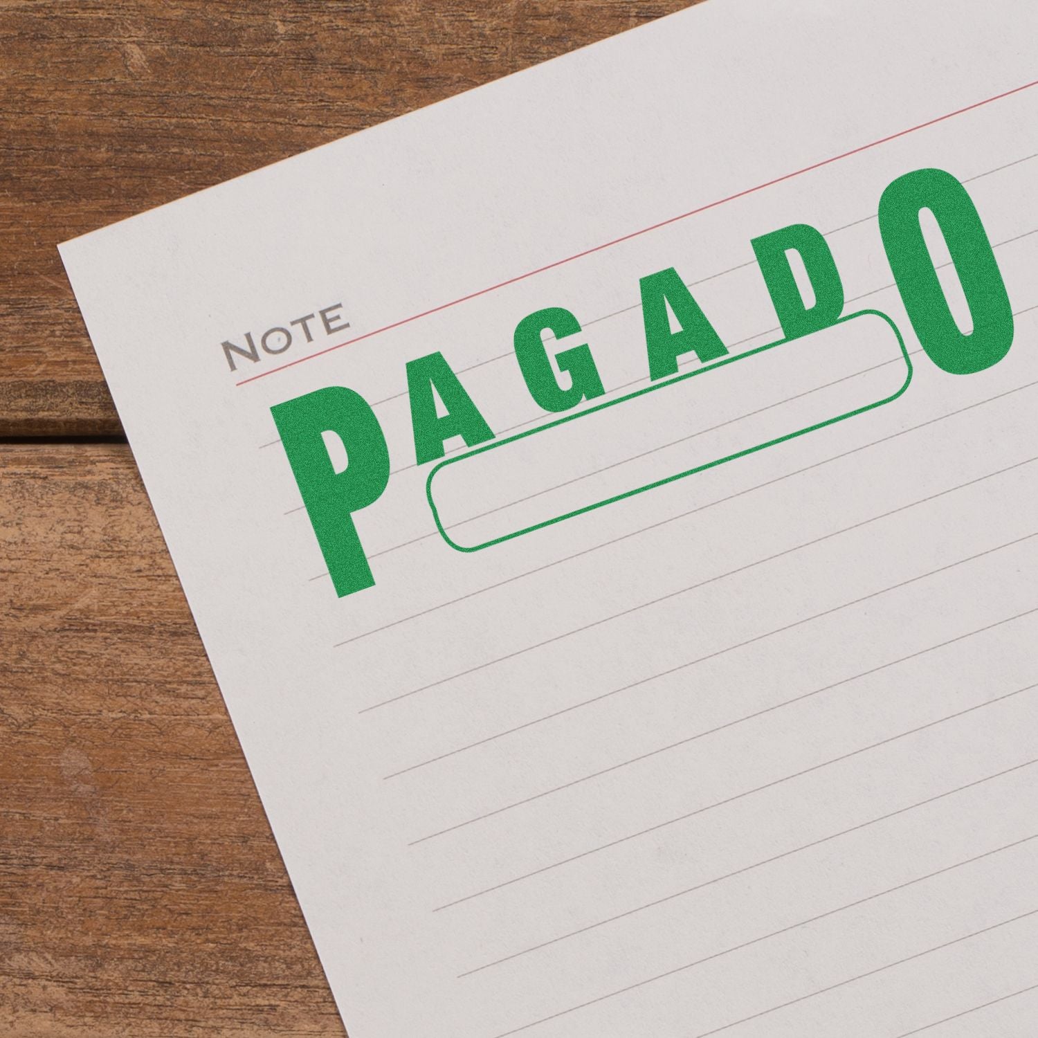 Slim Pre-Inked Pagado with Box Stamp in green ink on a lined note paper, placed on a wooden surface.