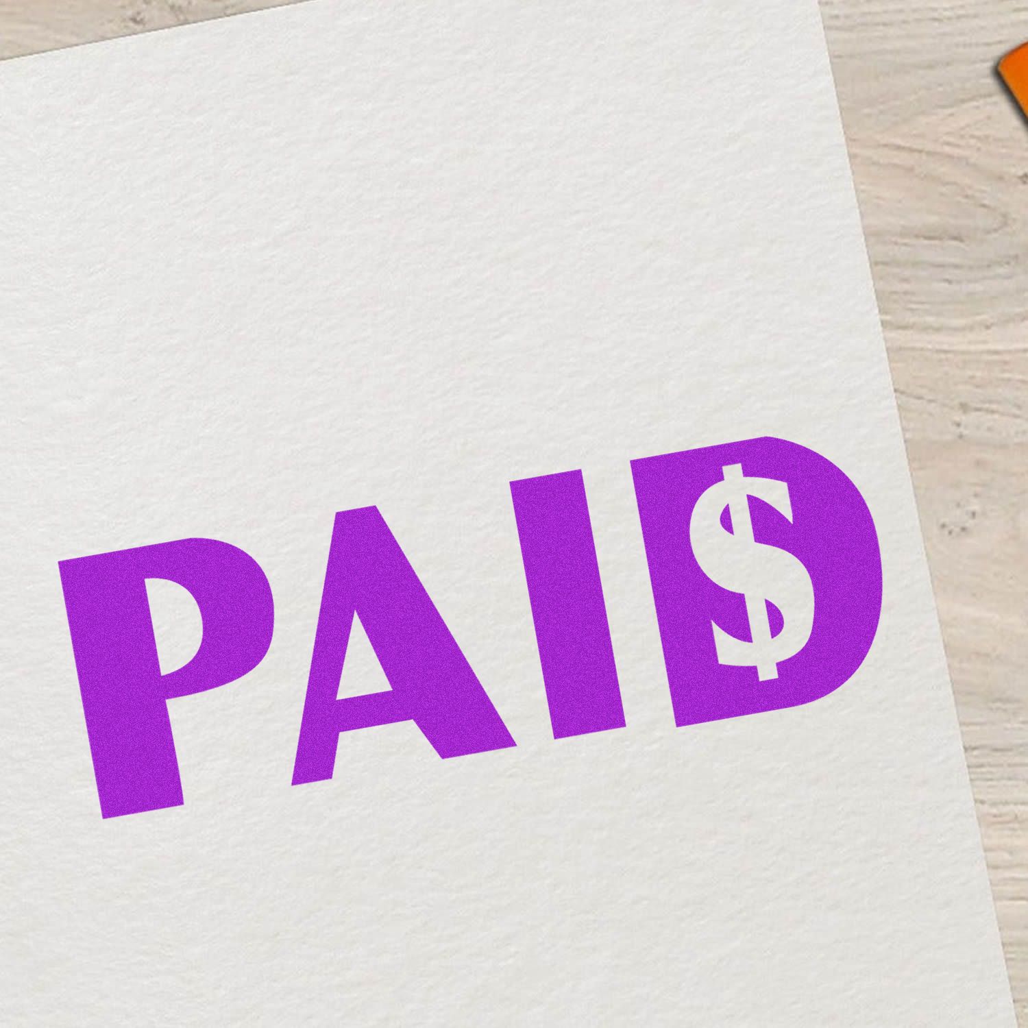 Paid with Dollar Sign Rubber Stamp in purple ink on white paper, placed on a light wooden surface.