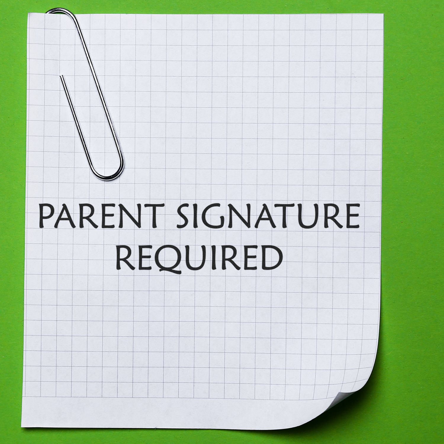 Slim Pre-Inked Parent Signature Required Stamp on a grid paper with a paperclip, placed on a green background.