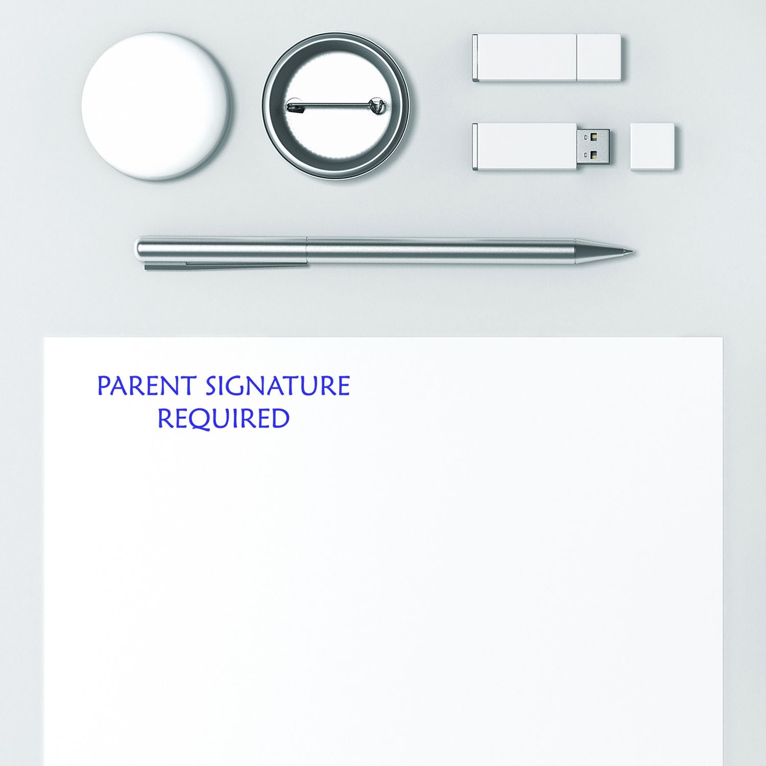 Slim Pre-Inked Parent Signature Required Stamp on white paper with office supplies: pen, badge, USB drives, and round container.