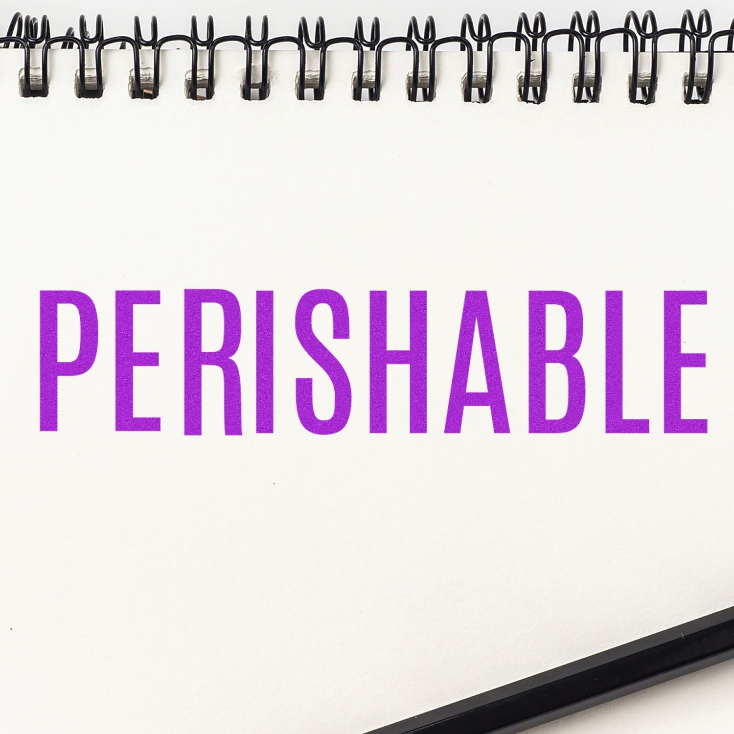 Slim Pre-Inked Perishable Stamp in use, displaying the word PERISHABLE in bold purple letters on a white notepad.