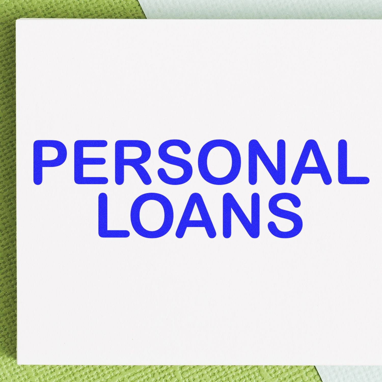 Personal Loans Rubber Stamp in blue ink on white paper, placed on a green textured surface.