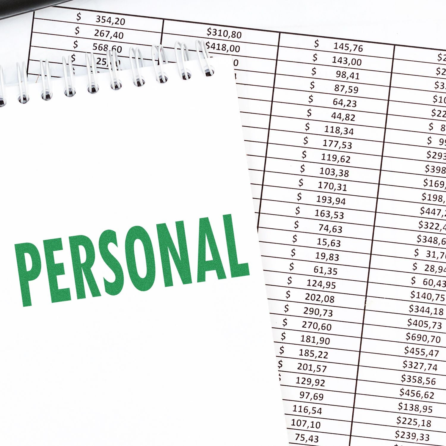 Slim Pre-Inked Personal Stamp used on a notebook with the word 'PERSONAL' stamped in green, next to financial documents.