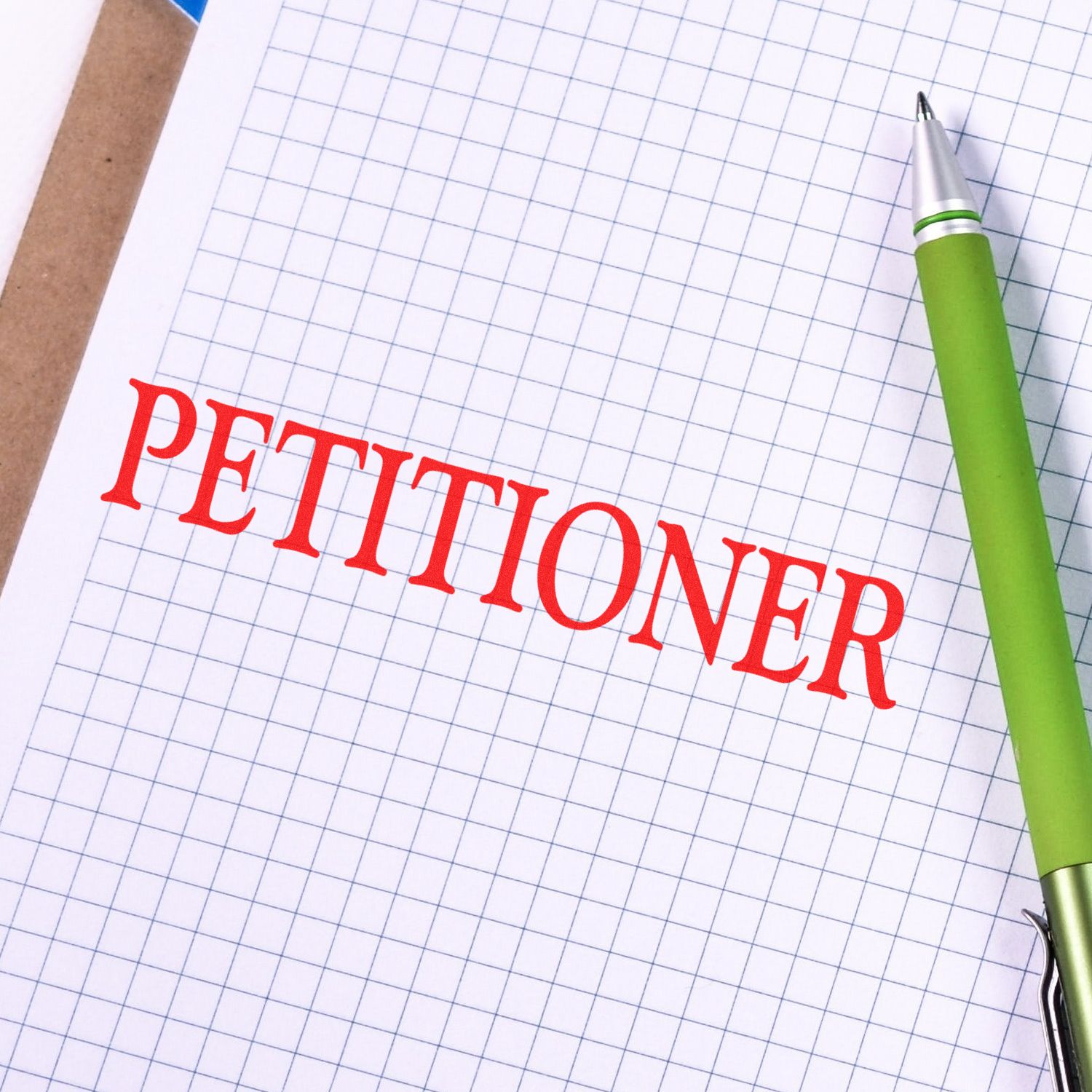 Petitioner Rubber Stamp in red ink on graph paper, next to a green pen.