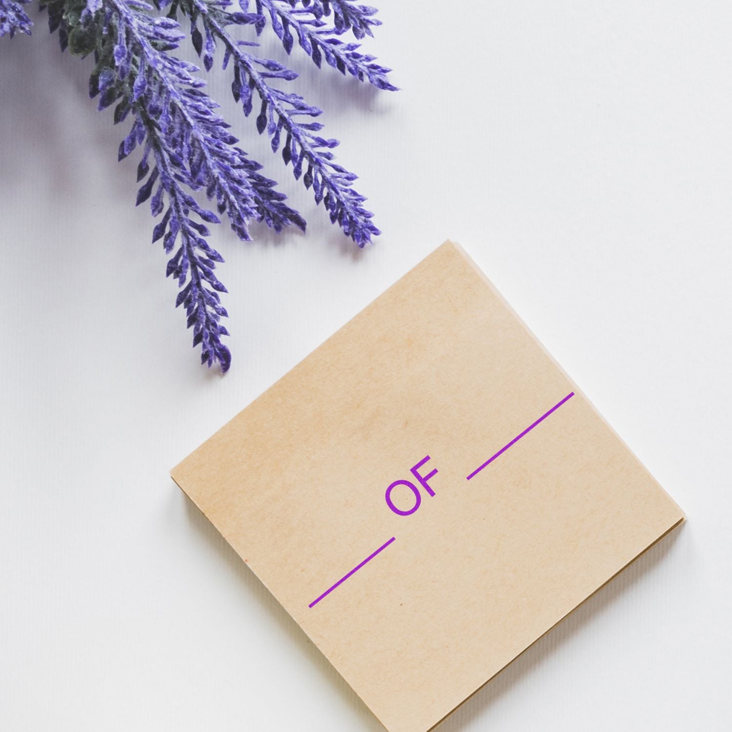 Large Pre-Inked Of Stamp on a beige square card with purple text, placed on a white surface next to lavender sprigs.