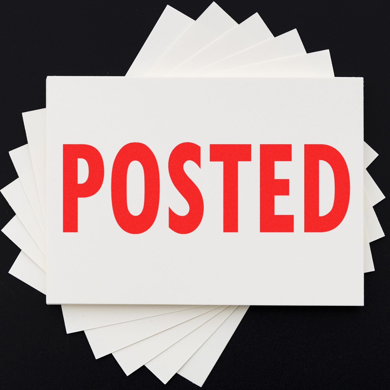 Posted rubber stamp in red ink on a white card, with multiple white cards fanned out underneath on a black background.