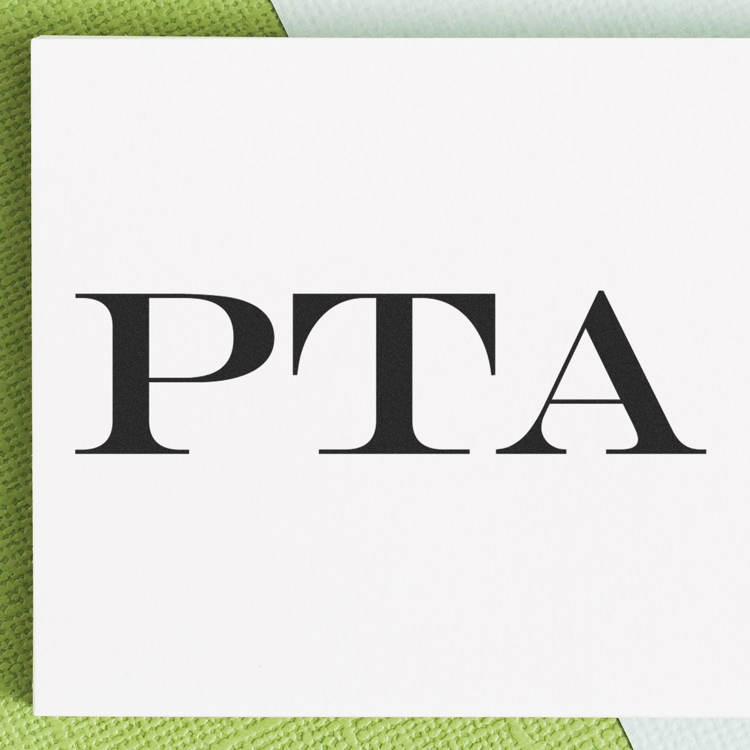 Large PTA Rubber Stamp imprint on white paper, showcasing bold black PTA text, placed on a green and white textured background.