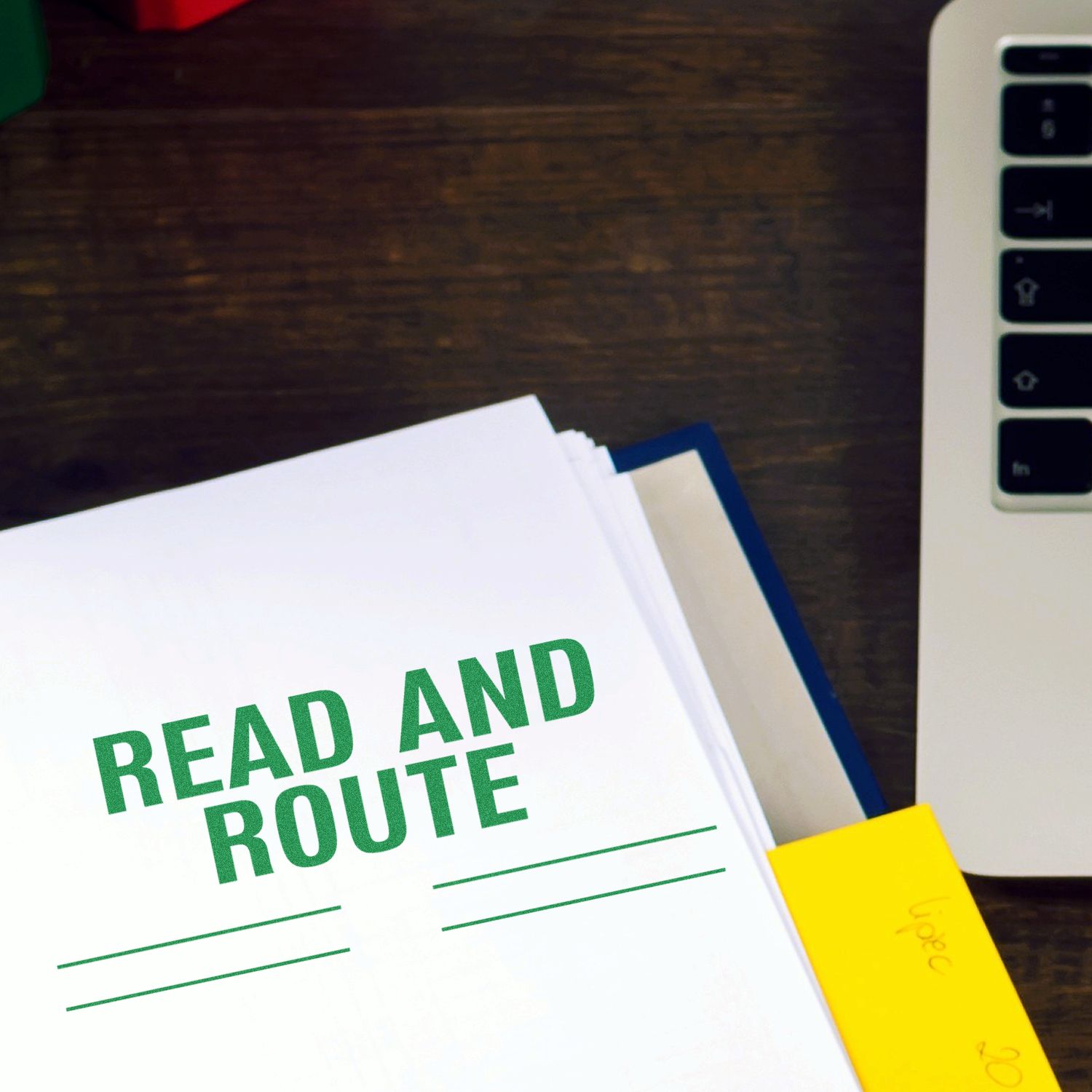 A stack of papers stamped with READ AND ROUTE using the Large Self Inking Read and Route with Lines Stamp, next to a laptop on a desk.