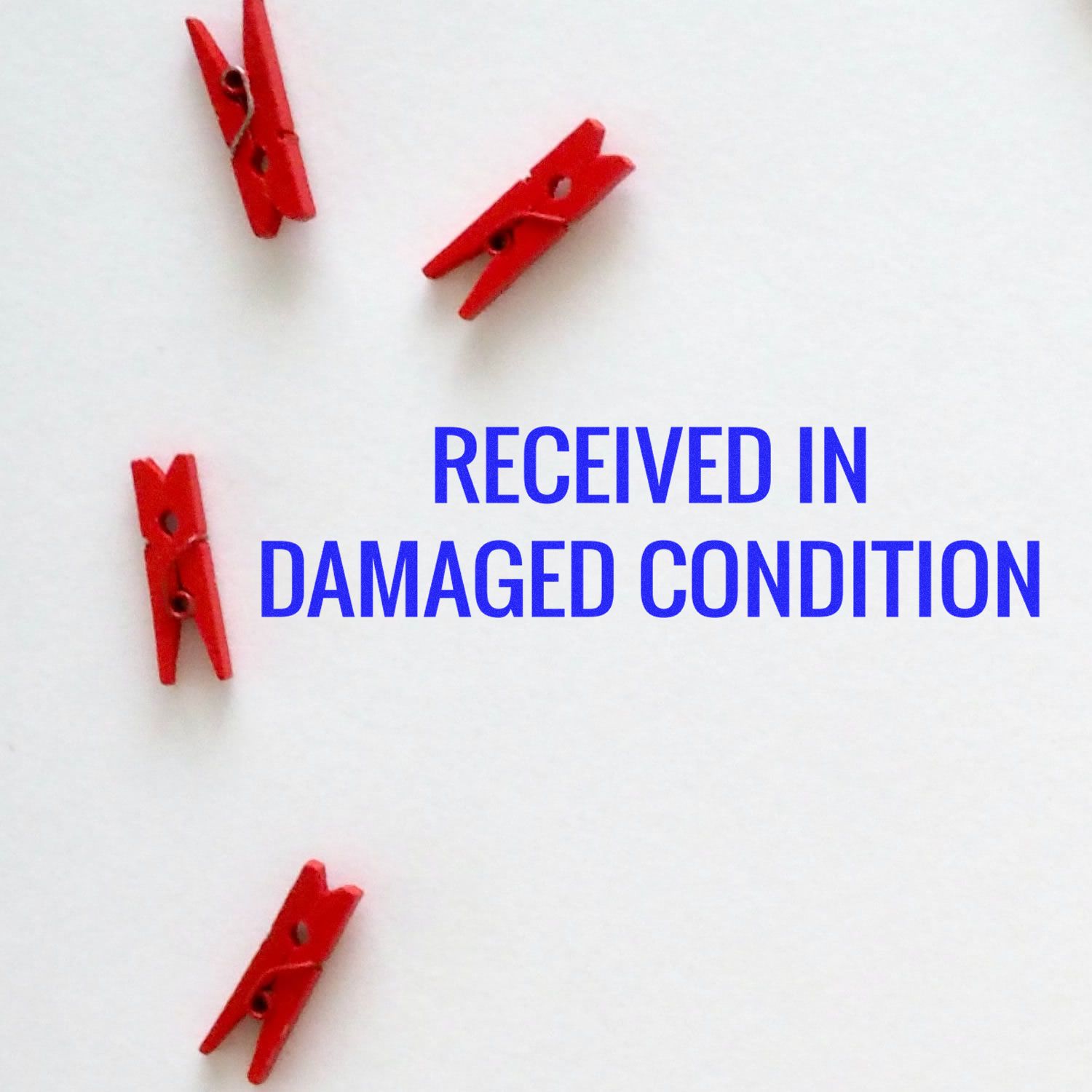 Received in Damaged Condition Rubber Stamp in blue text on white background with four red clothespins scattered around.