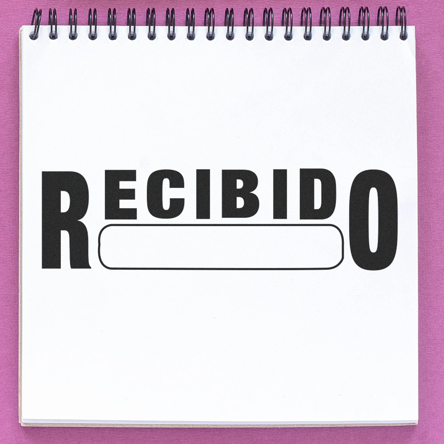 Slim Pre-Inked Recibido Stamp in use on a white notepad with a pink background. The stamp prints "RECIBIDO" in bold black letters.