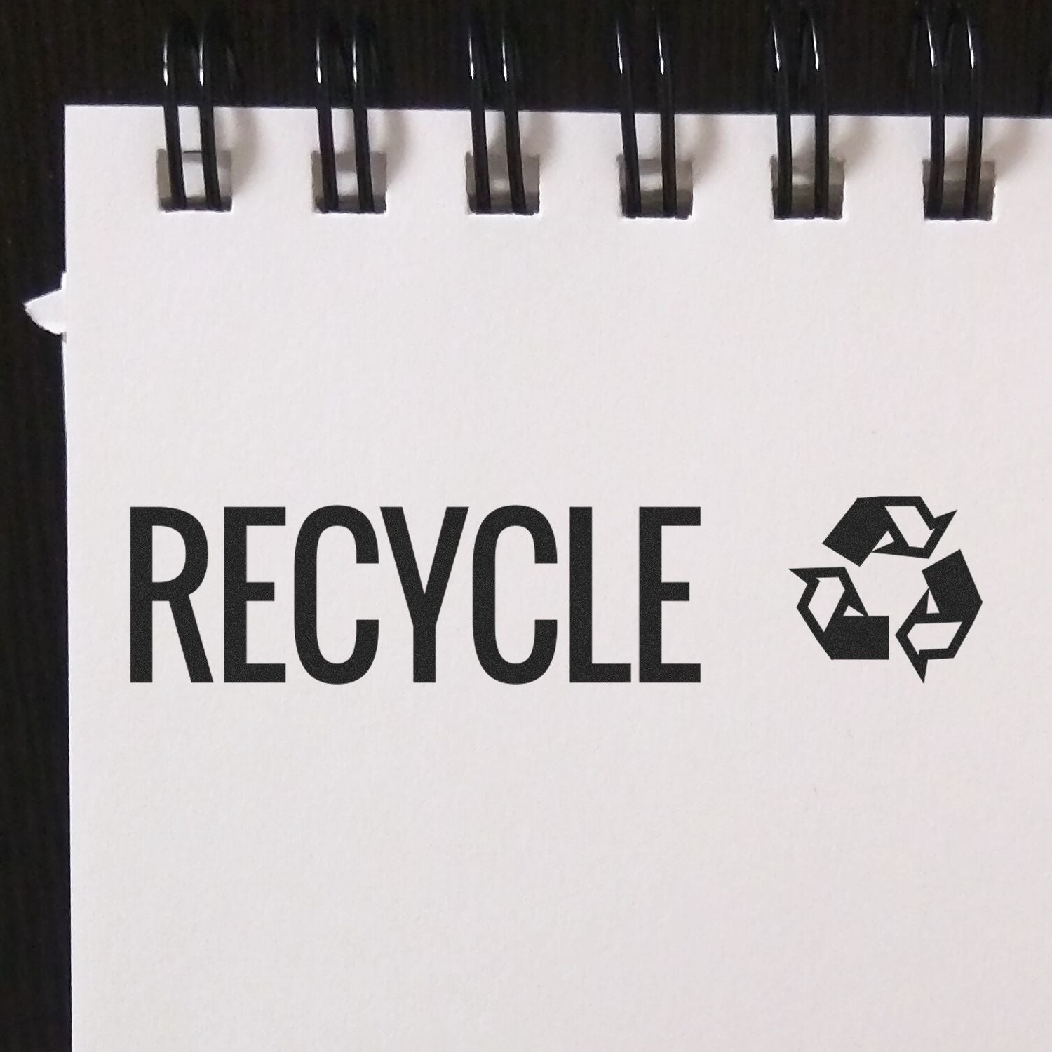 Slim Pre-Inked Recycle with Logo Stamp on white paper with black spiral binding, featuring the word RECYCLE and a recycle symbol.