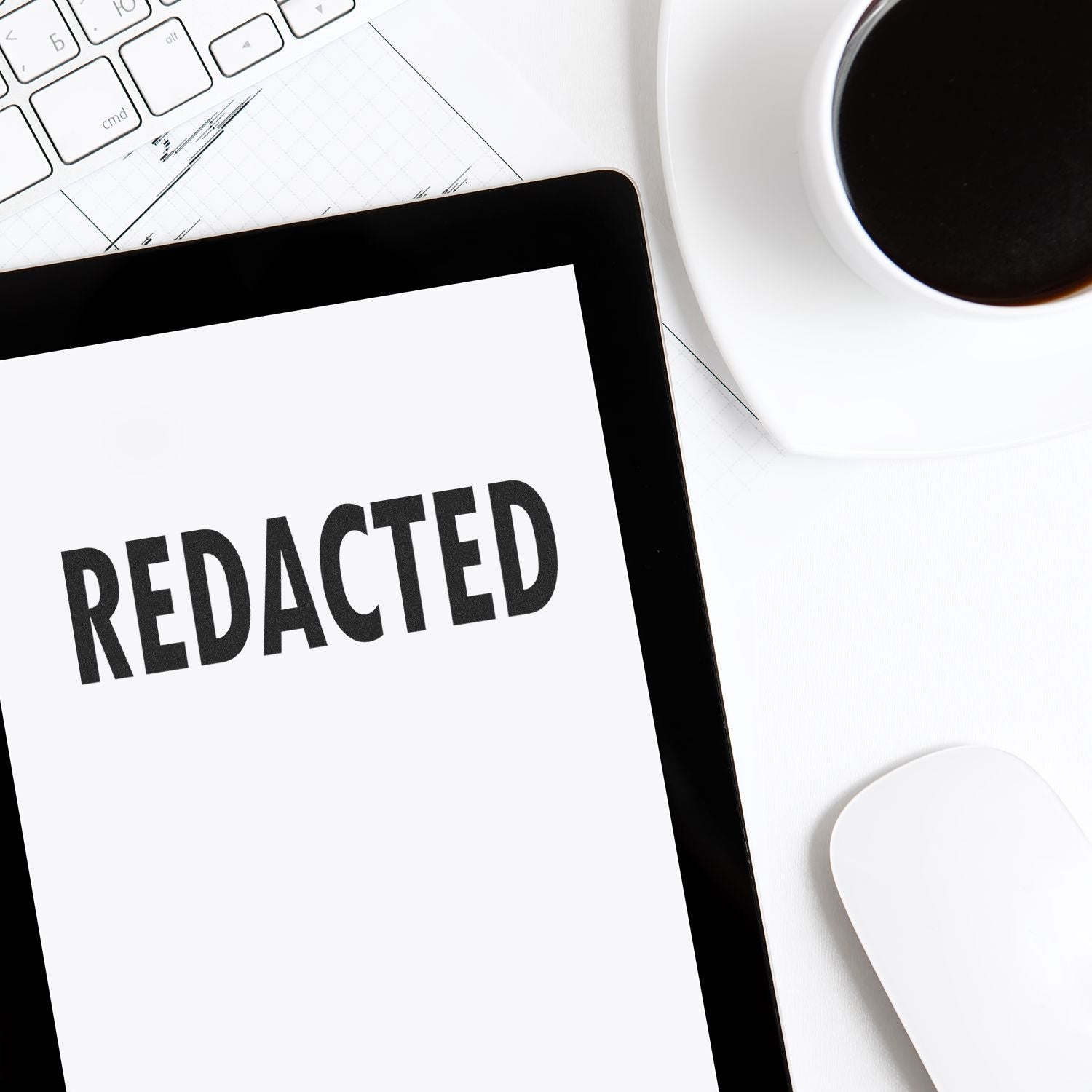 Large Pre-Inked Redacted Stamp used on a document, placed on a desk with a keyboard, mouse, and a cup of coffee nearby.