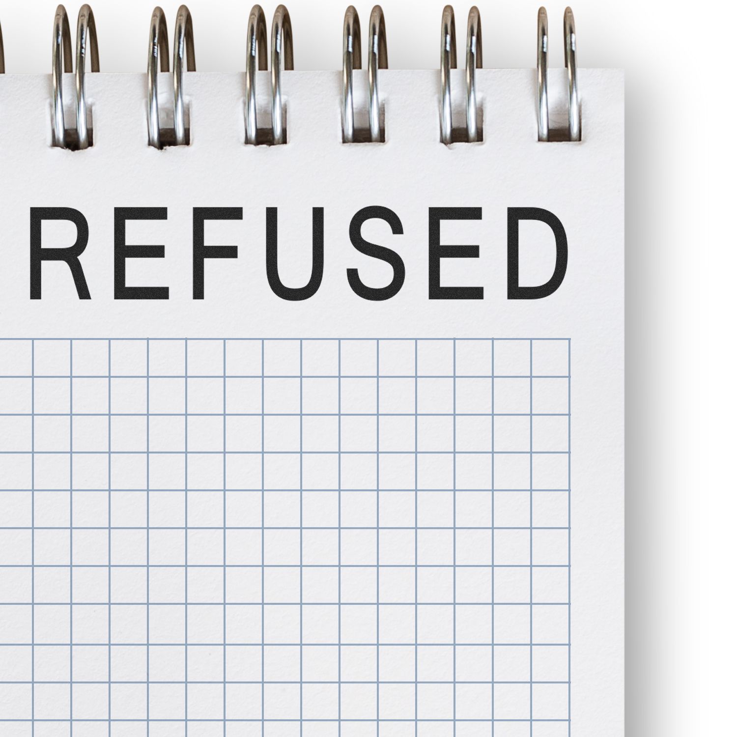 Slim Pre-Inked Refused Stamp marking 'REFUSED' in bold black letters on a spiral-bound notepad with a grid pattern.