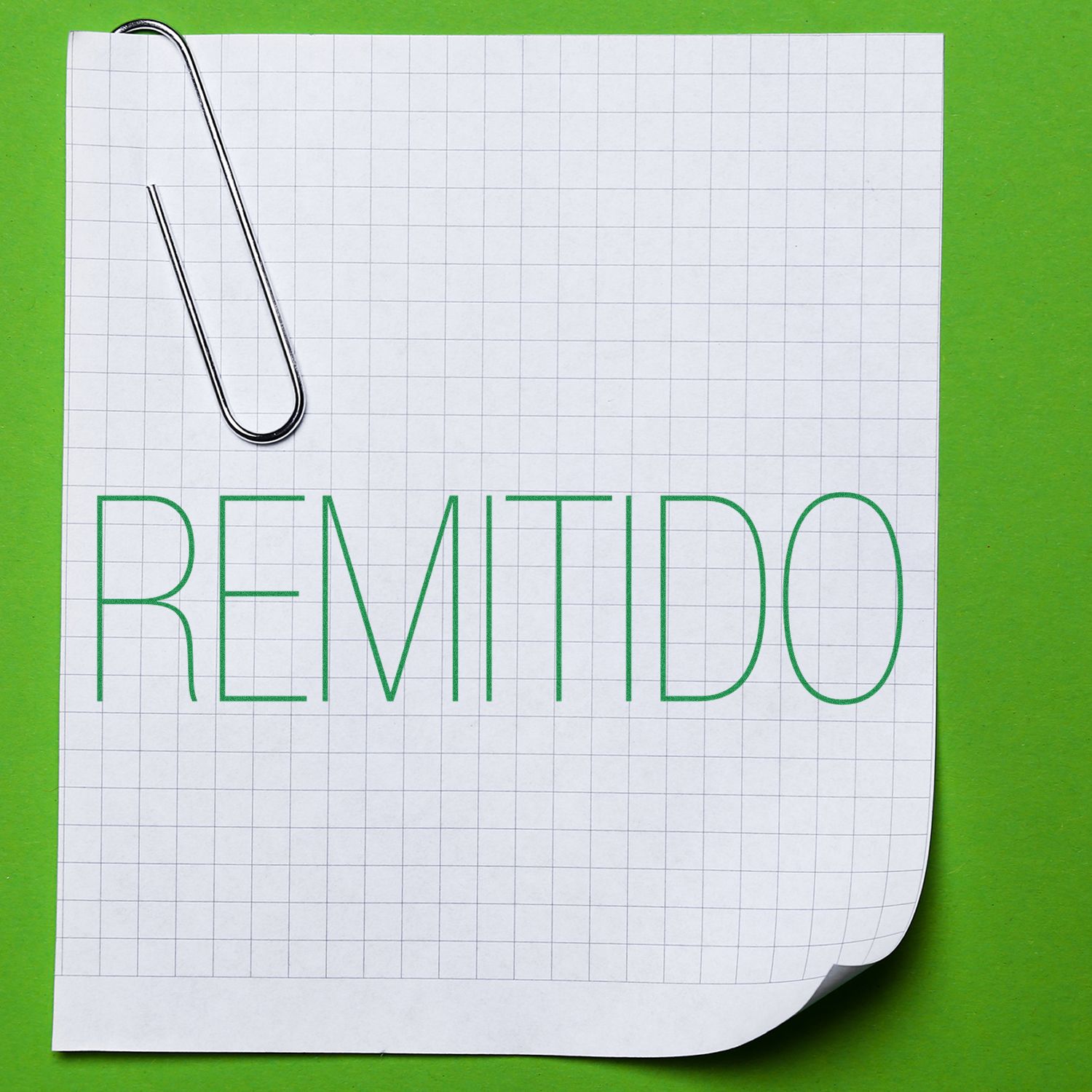 Remitido Rubber Stamp on a white graph paper with a paperclip, placed on a green background.