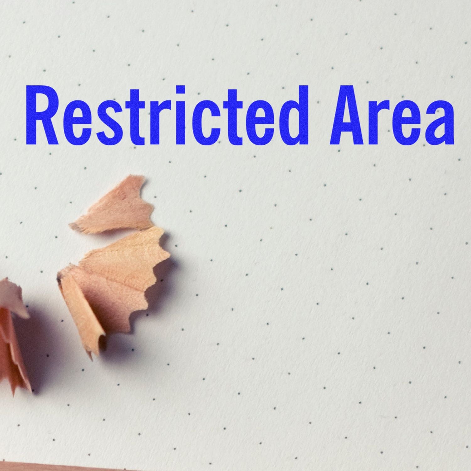 Restricted Area Rubber Stamp impression on dotted paper with pencil shavings nearby.