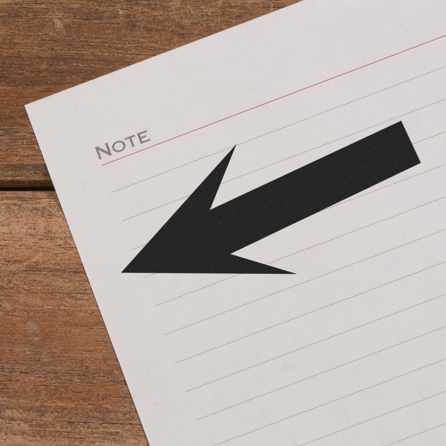 Round Arrow Rubber Stamp in black ink on lined paper with the word Note at the top, placed on a wooden surface.