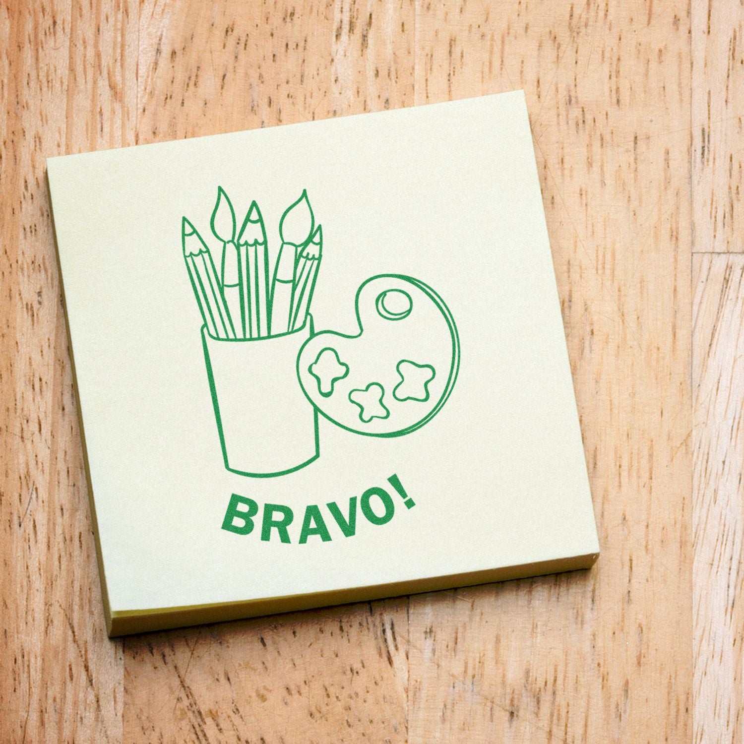 Round Bravo Rubber Stamp on a sticky note with a green illustration of art supplies and the word 'BRAVO!' underneath.