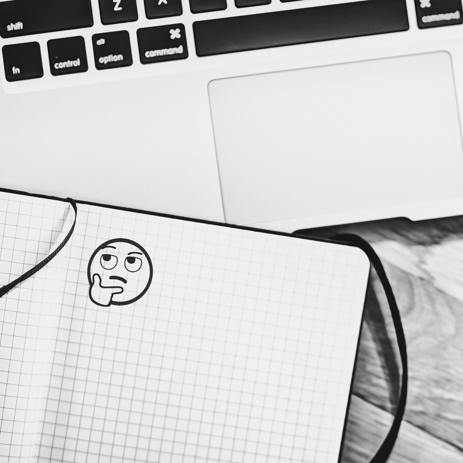 Round Curious Smiley Rubber Stamp impression on a grid notebook page next to a laptop keyboard.