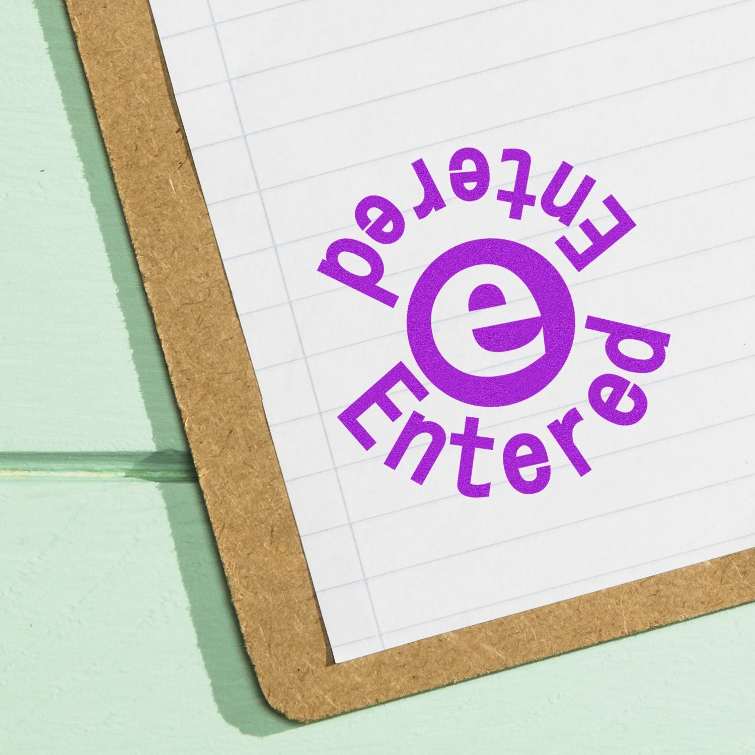 A clipboard with a sheet of paper stamped with a purple round Entered Entered rubber stamp.