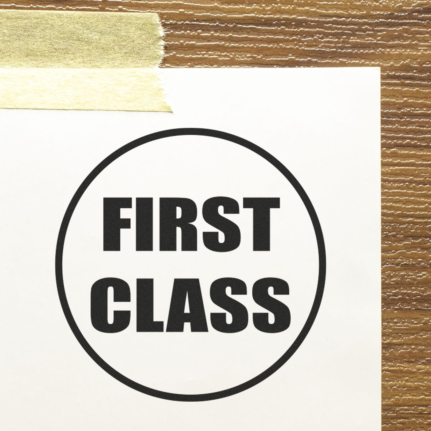 Round First Class Rubber Stamp on white paper taped to a wooden surface, displaying bold black text "FIRST CLASS" inside a circle.