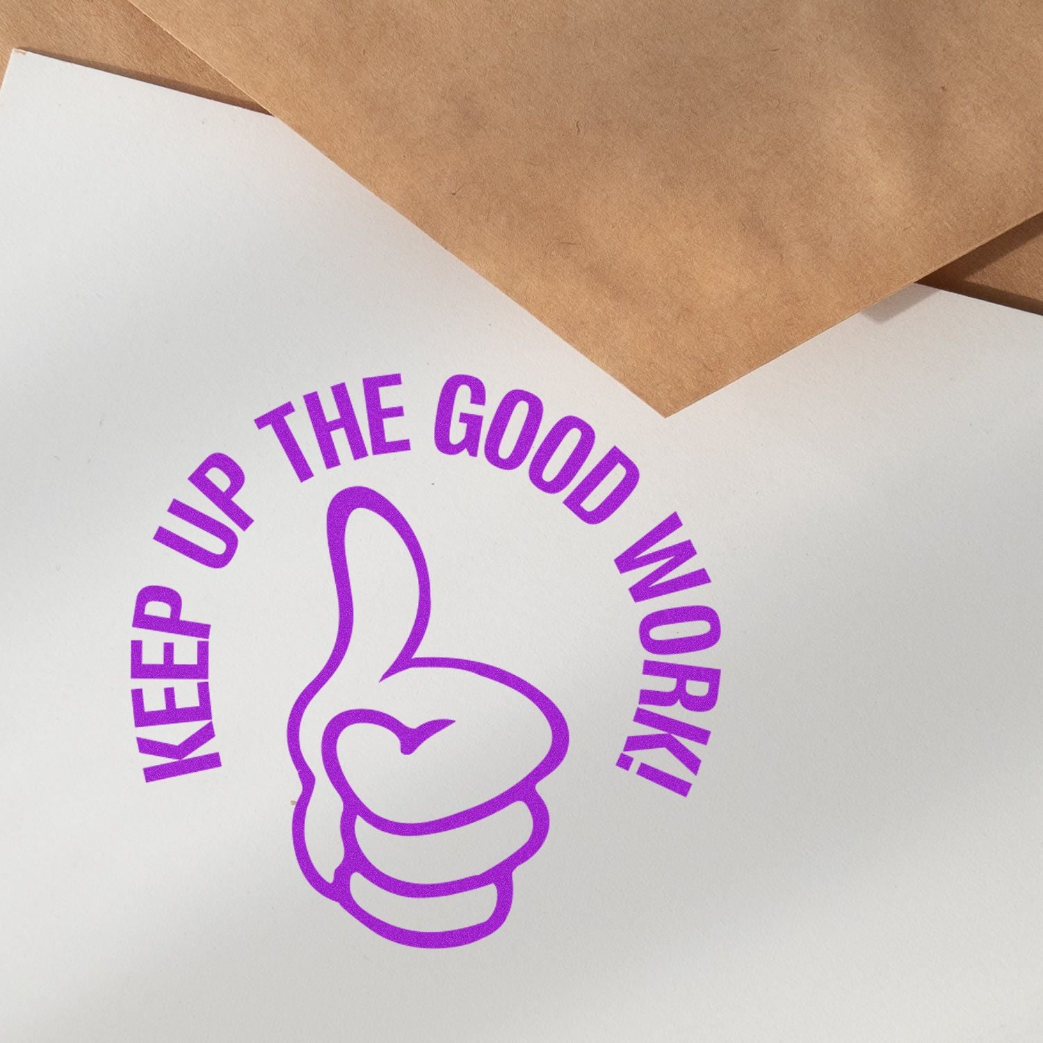 Round Keep up the Good Work rubber stamp in purple ink on white paper, with brown envelopes in the background.