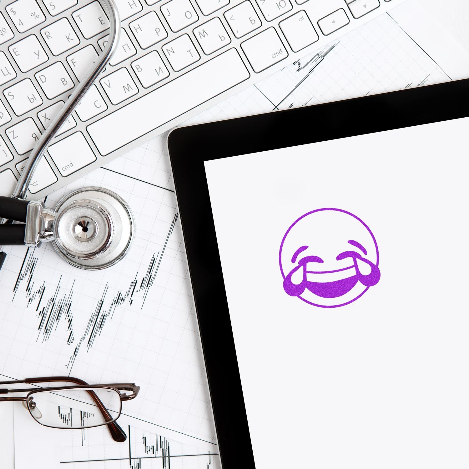 Round Laughing Smiley Rubber Stamp in purple ink on paper, surrounded by a stethoscope, keyboard, glasses, and tablet.