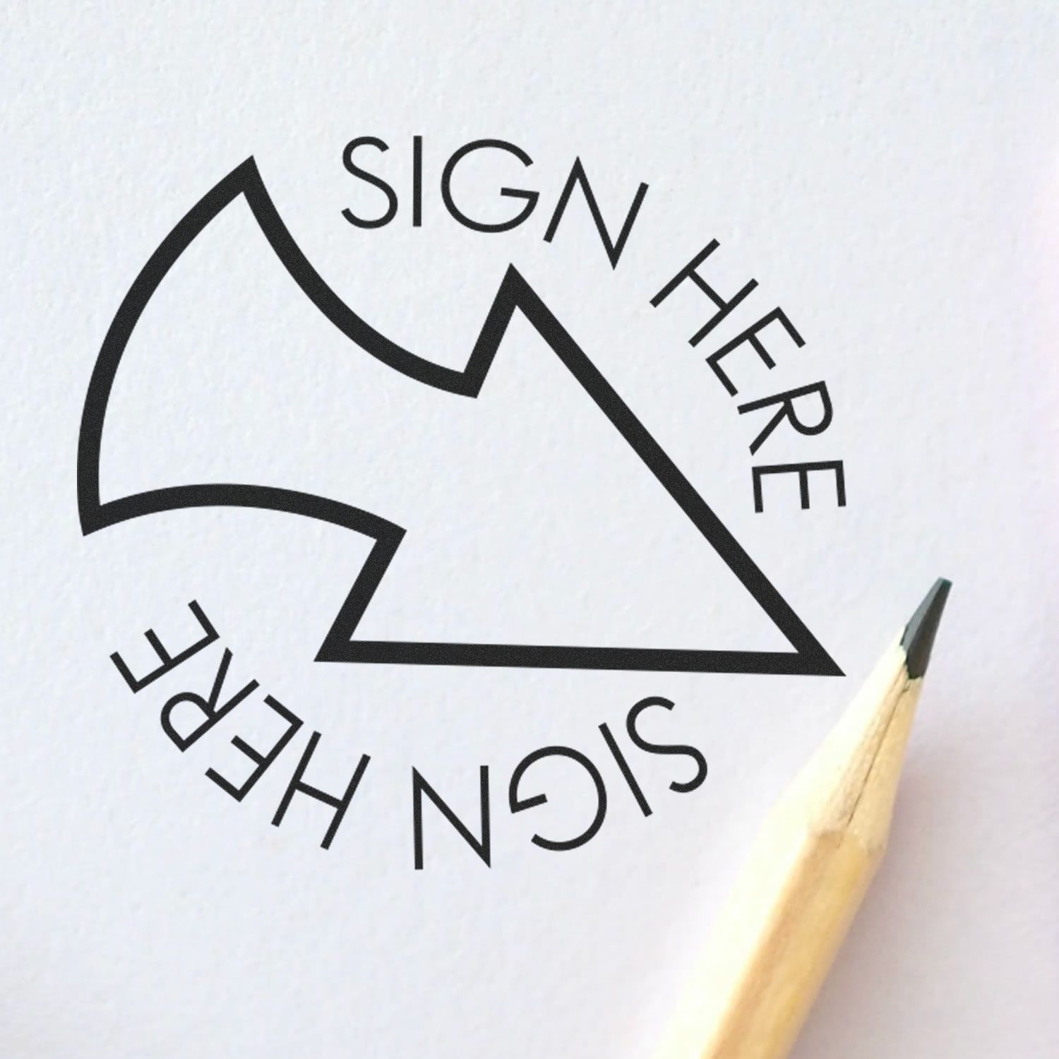 Round Sign Here with Arrow Rubber Stamp impression on white paper with a pencil tip pointing towards the stamp.