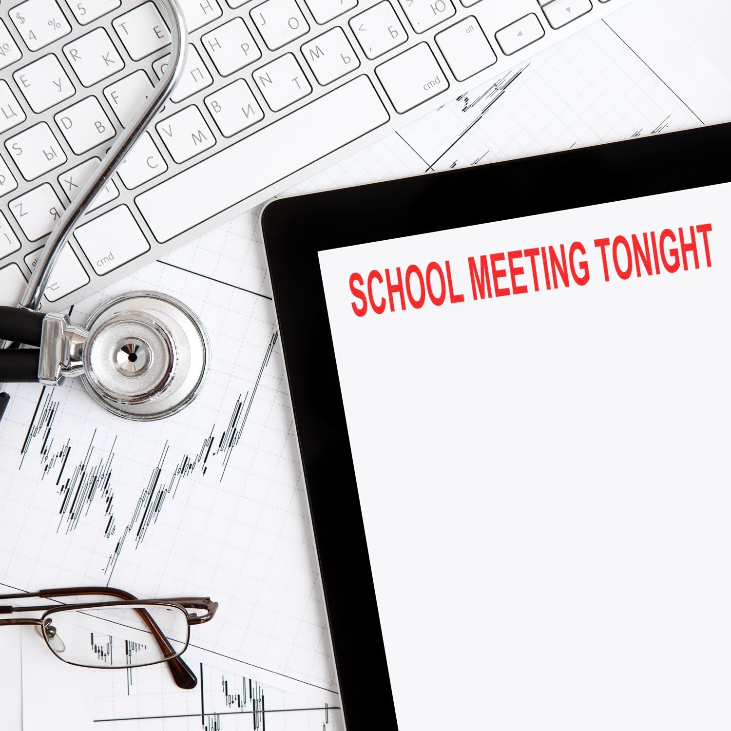 School Meeting Tonight rubber stamp on paper beside a keyboard, stethoscope, glasses, and graph papers.