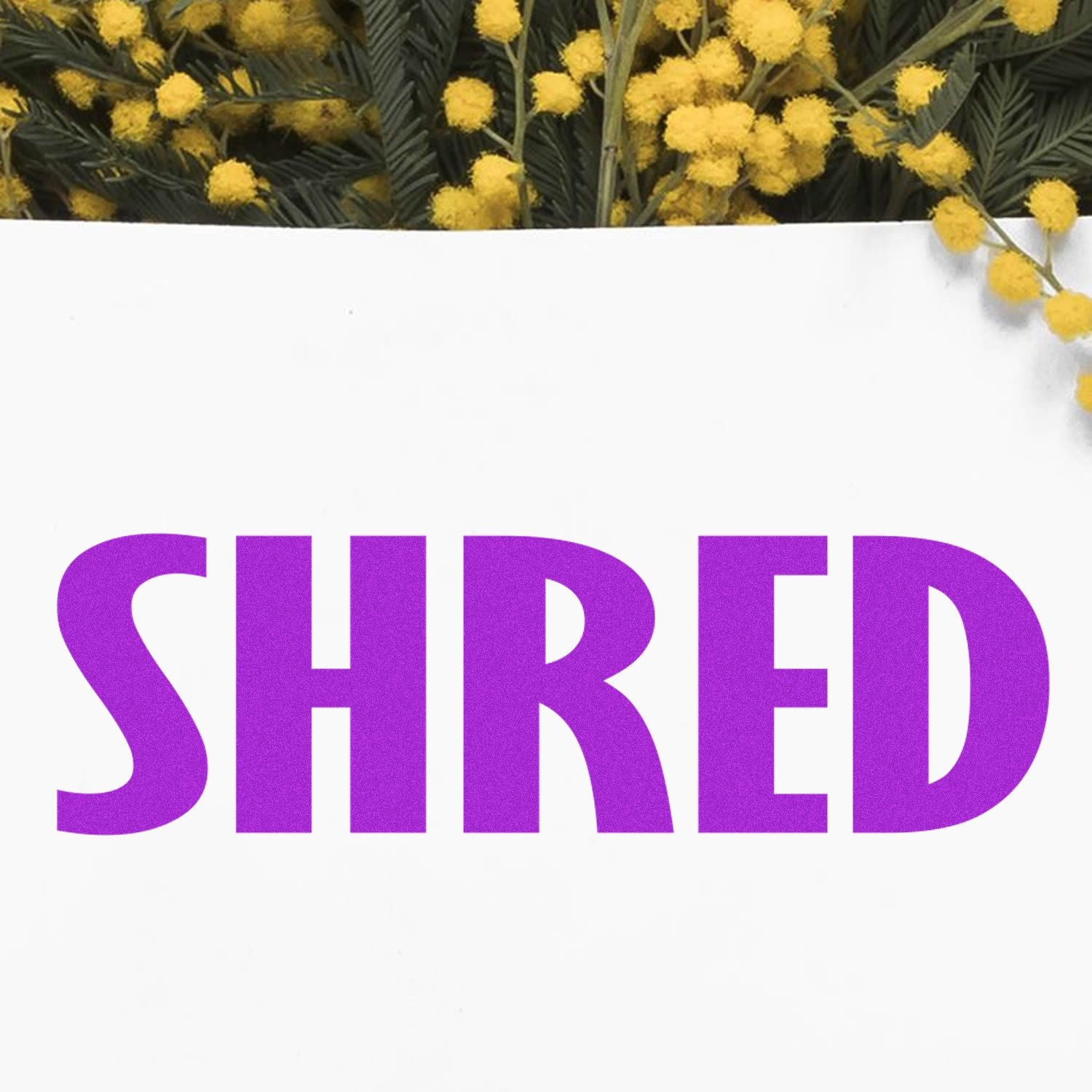 Shred Rubber Stamp in use, displaying the word "SHRED" in bold purple letters on white paper with yellow flowers in the background.