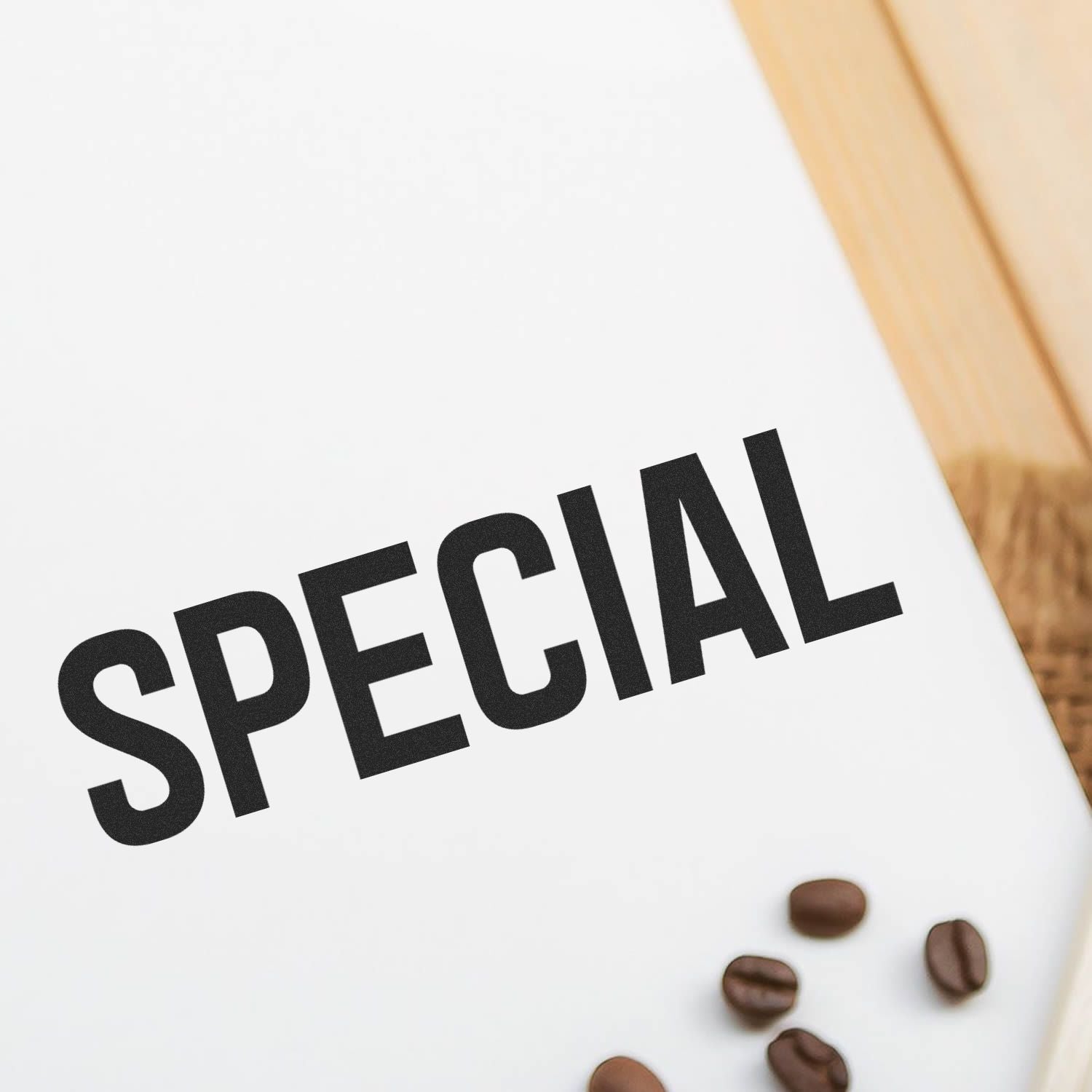 Self Inking Special Stamp imprinting the word SPECIAL on white paper, with coffee beans scattered on a wooden surface nearby.