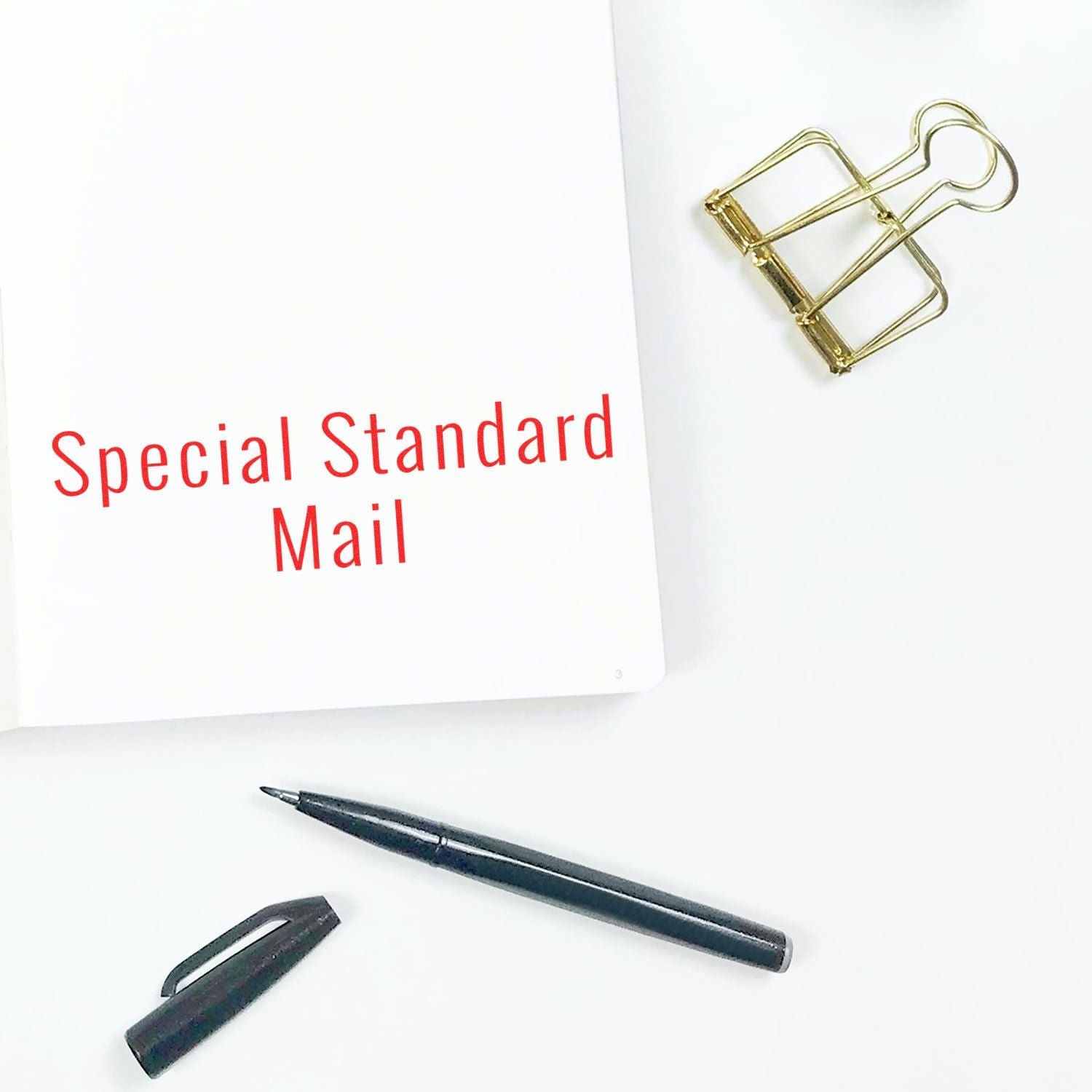 Large Self Inking Special Standard Mail Stamp used on white paper, with a pen, binder clip, and pen cap nearby on a white surface.