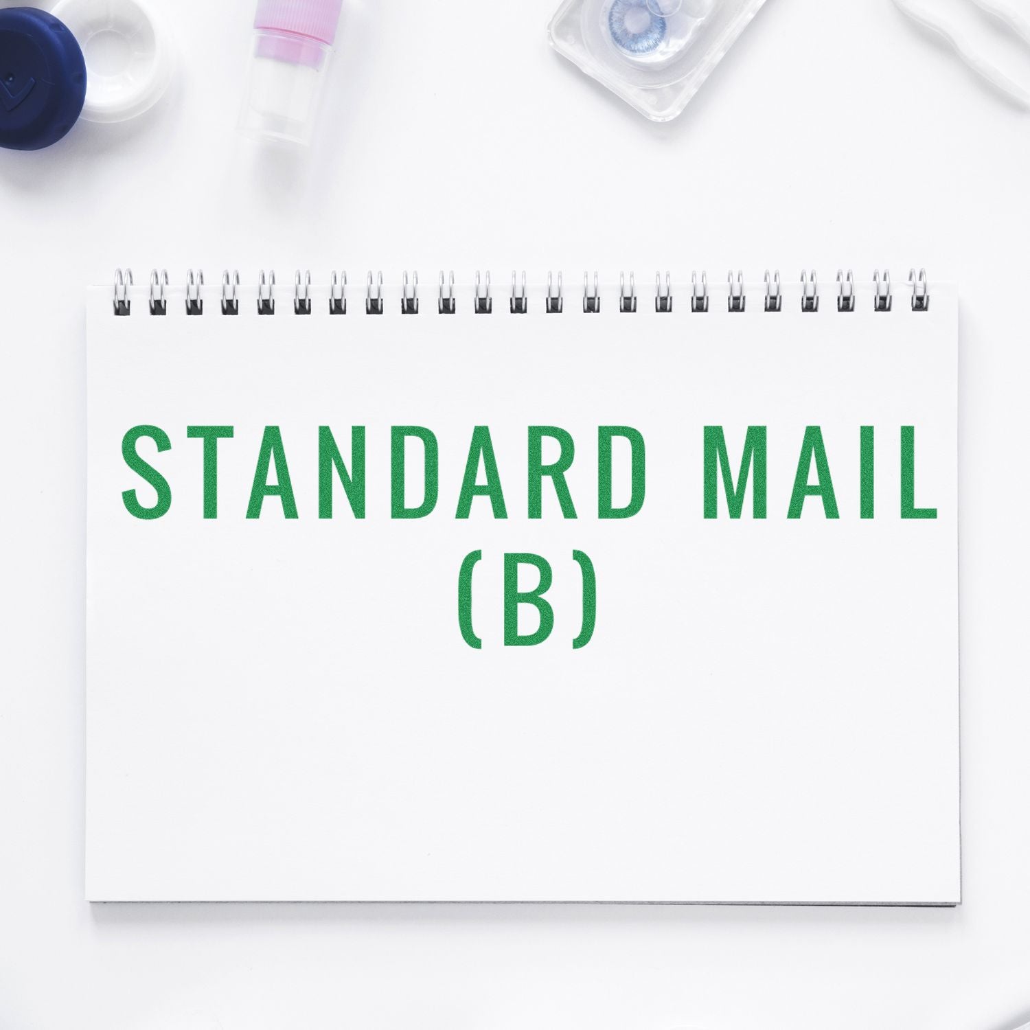 A notebook with "Standard Mail (B)" stamped in green ink, surrounded by office supplies on a white background.