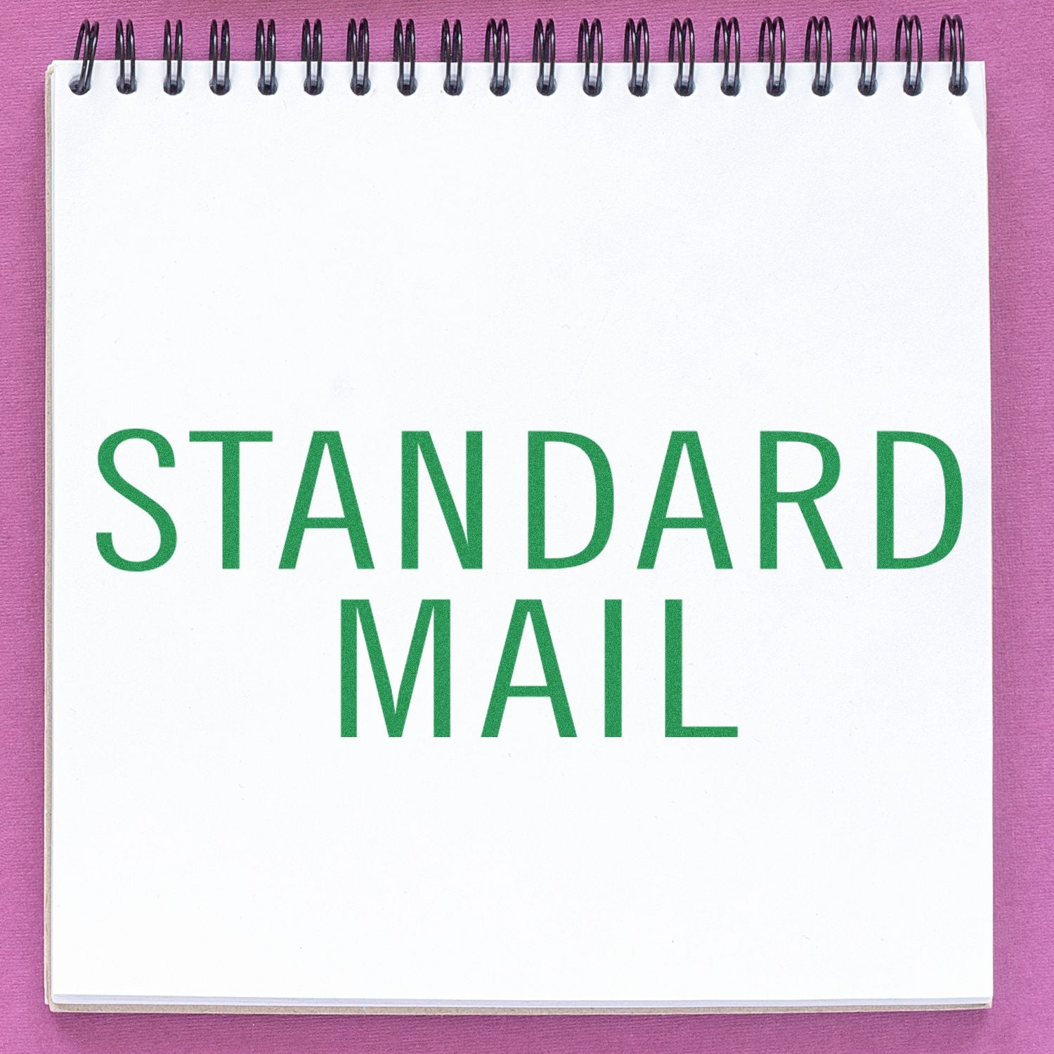 Notebook with 'STANDARD MAIL' stamped in green, using a Standard Mail Stacked Rubber Stamp, on a pink background.