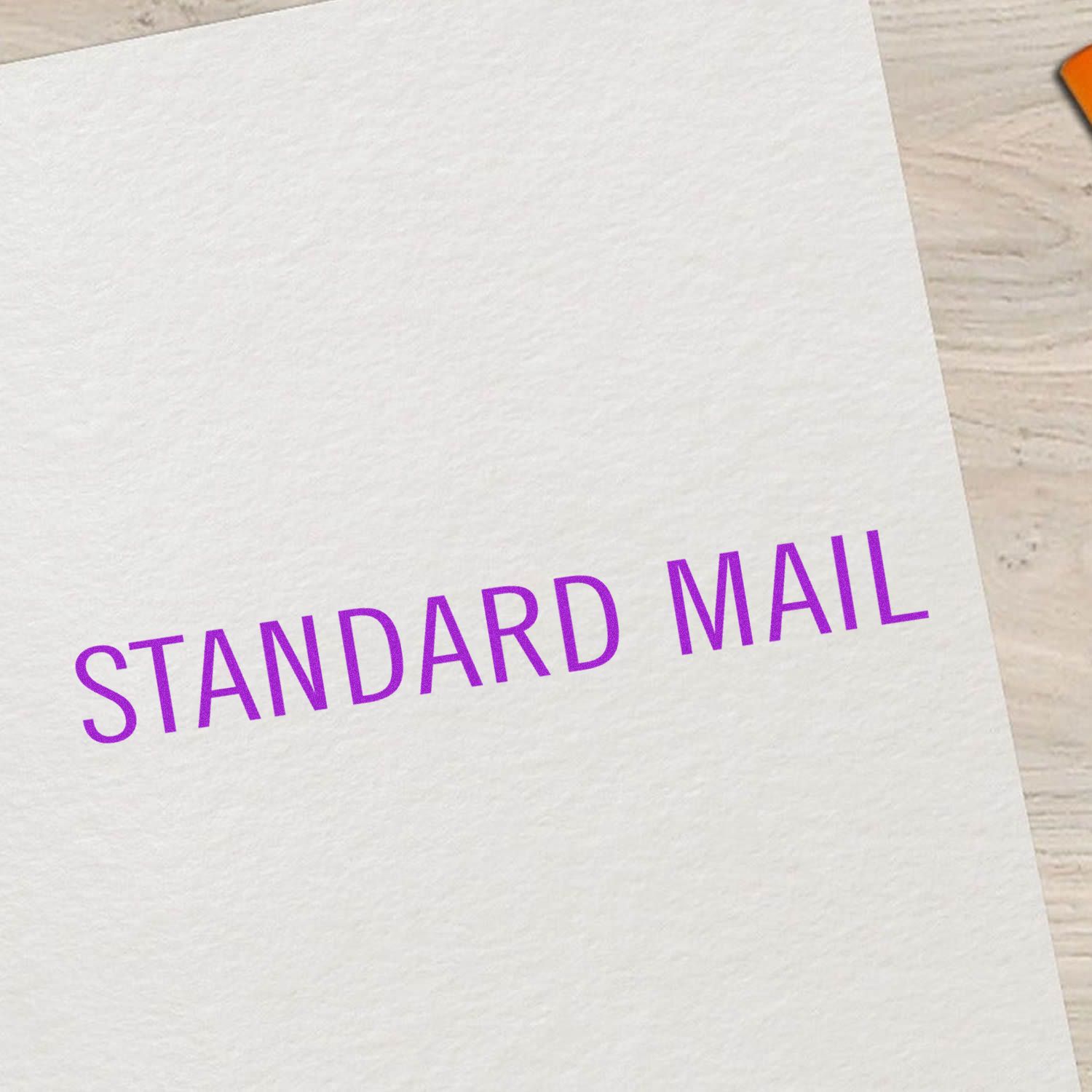 Large Self Inking Standard Mail Stamp imprinting STANDARD MAIL in purple ink on a white sheet, placed on a light wooden surface.