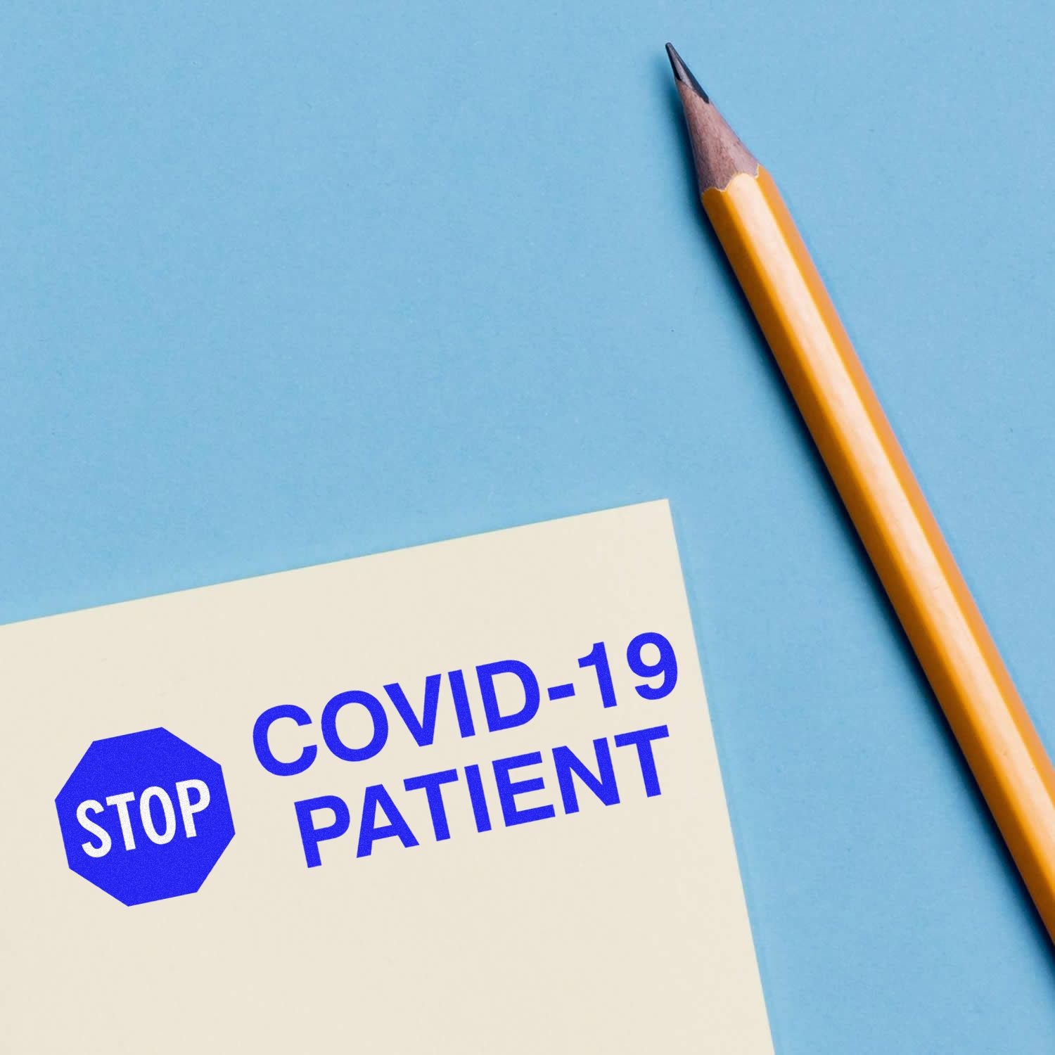 Stop Covid-19 Patient rubber stamp on paper next to a yellow pencil on a blue background.