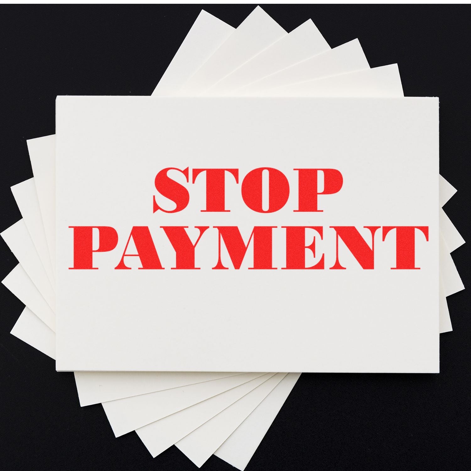 Large Self Inking Stop Payment Stamp in red ink on white paper, with multiple sheets fanned out underneath on a black background.