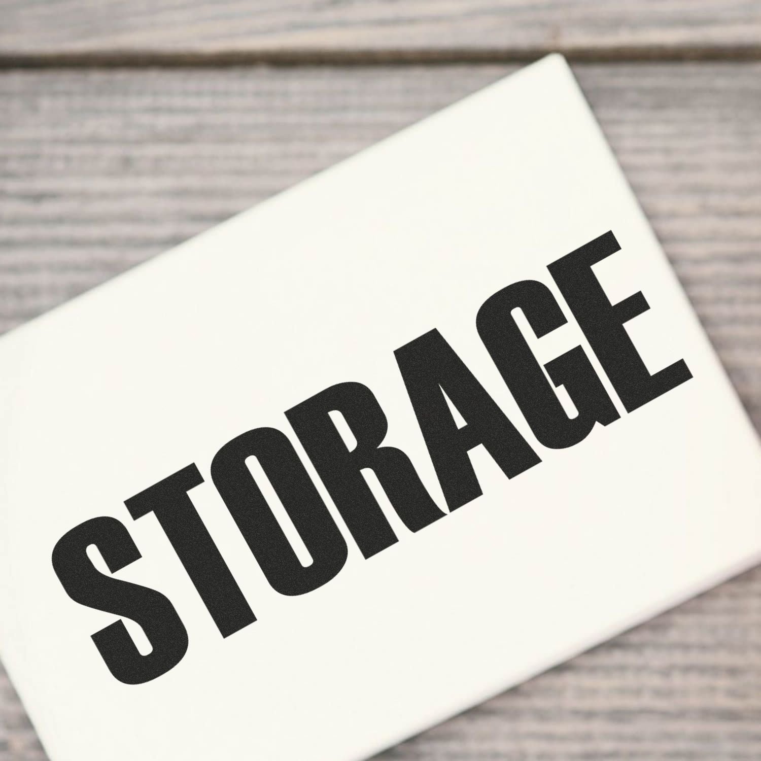 Large Self Inking Storage Stamp marking the word STORAGE in bold black letters on a white surface, placed on a wooden background.