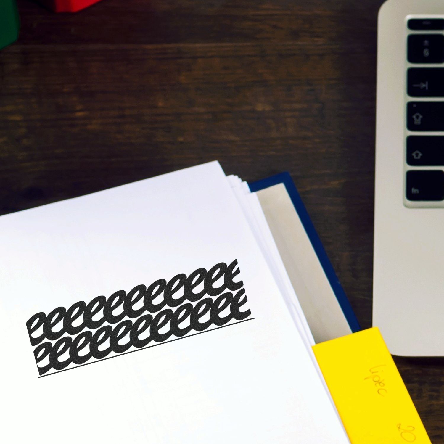 Self Inking Strikeout Stamp in use, black strikeout marks on white paper, placed on a wooden desk next to a laptop and sticky notes.