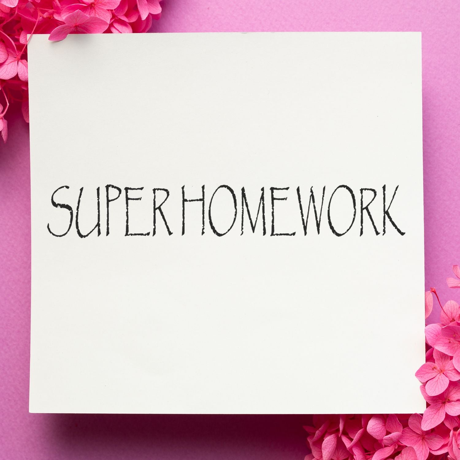 Slim Pre-Inked Super Homework Stamp used on white paper with pink flowers on a pink background.