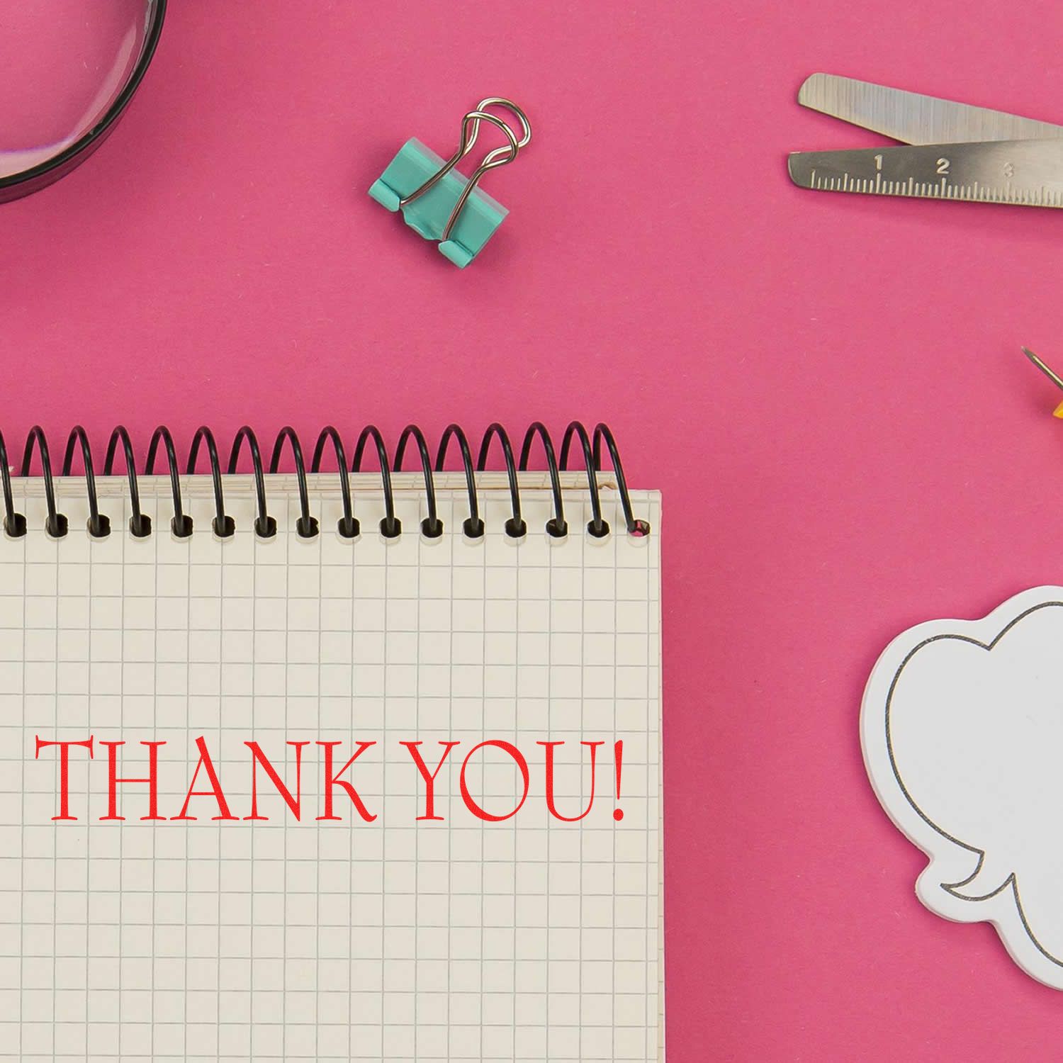 Thank You Rubber Stamp used on a notebook with grid paper, surrounded by office supplies on a pink background.