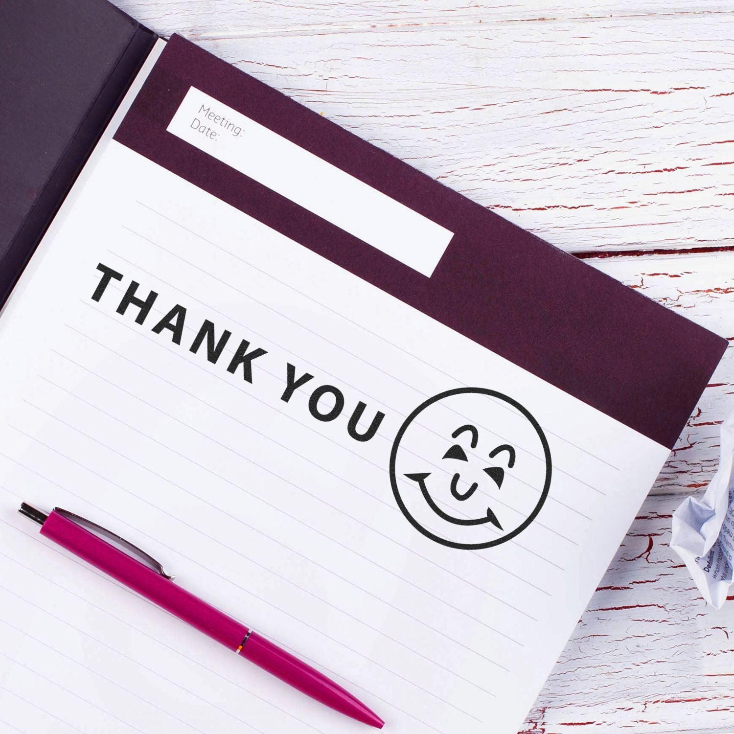 Large Self Inking Thank You with Smiley Stamp on a notebook page with a pink pen beside it.