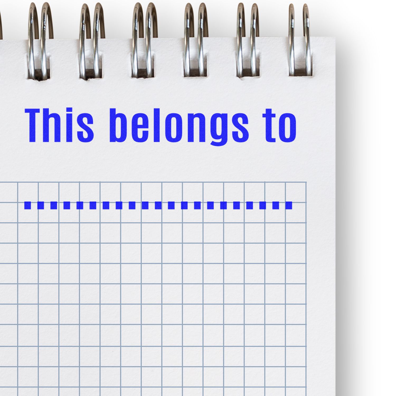 A notebook with a grid pattern and the text "This belongs to" stamped in blue using the "This belongs to ... Rubber Stamp."