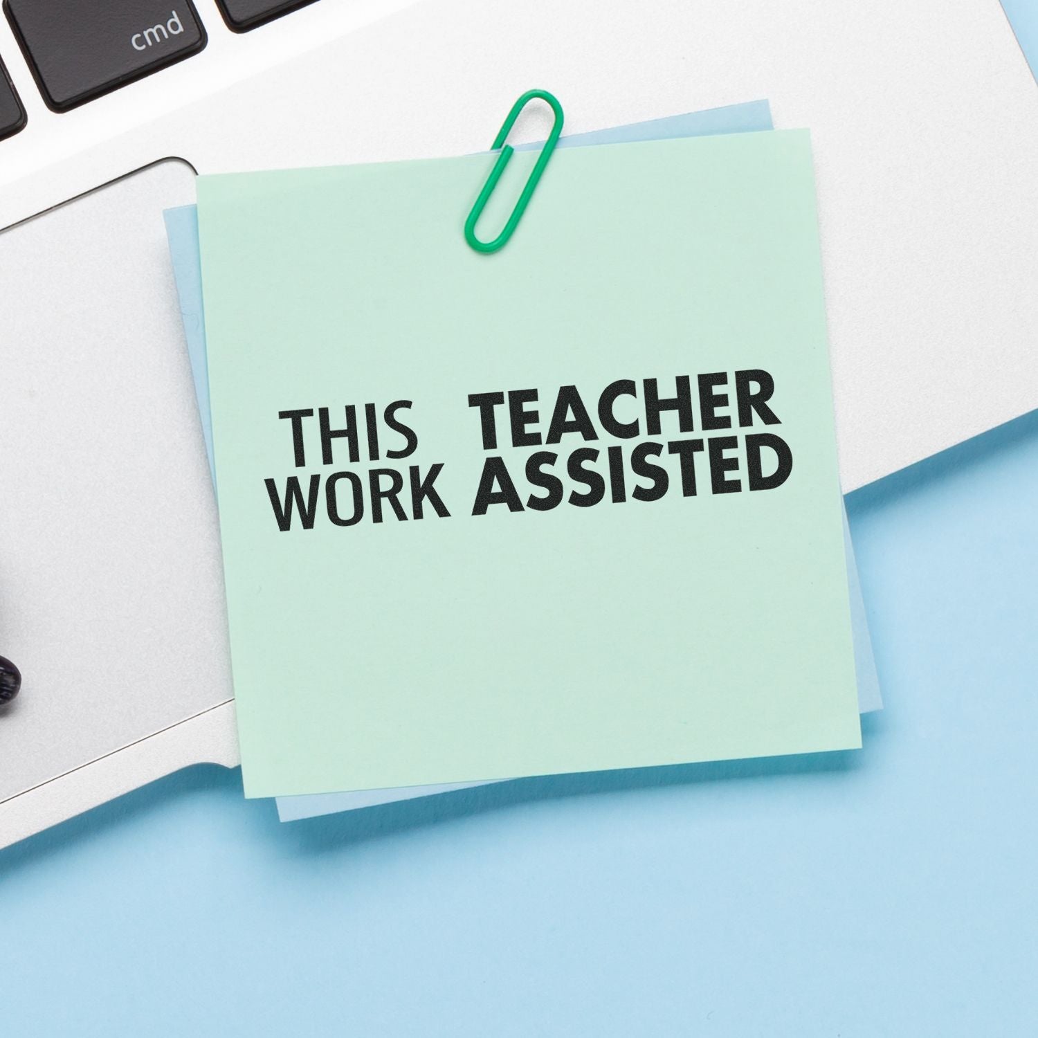 A Large Self Inking This Work Teacher Assisted Stamp is used on a green sticky note clipped to a laptop, indicating teacher assistance.