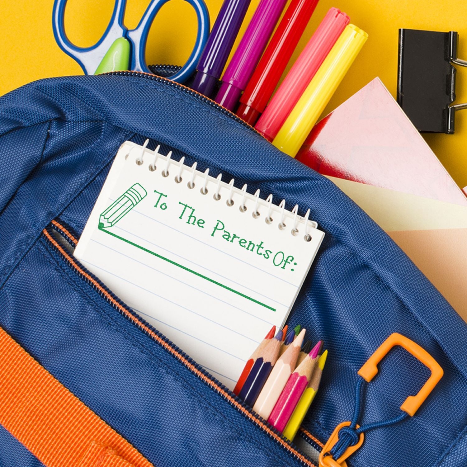 Blue backpack with school supplies and a notebook stamped with Large Self Inking To The Parents Of with Line Stamp in green ink.