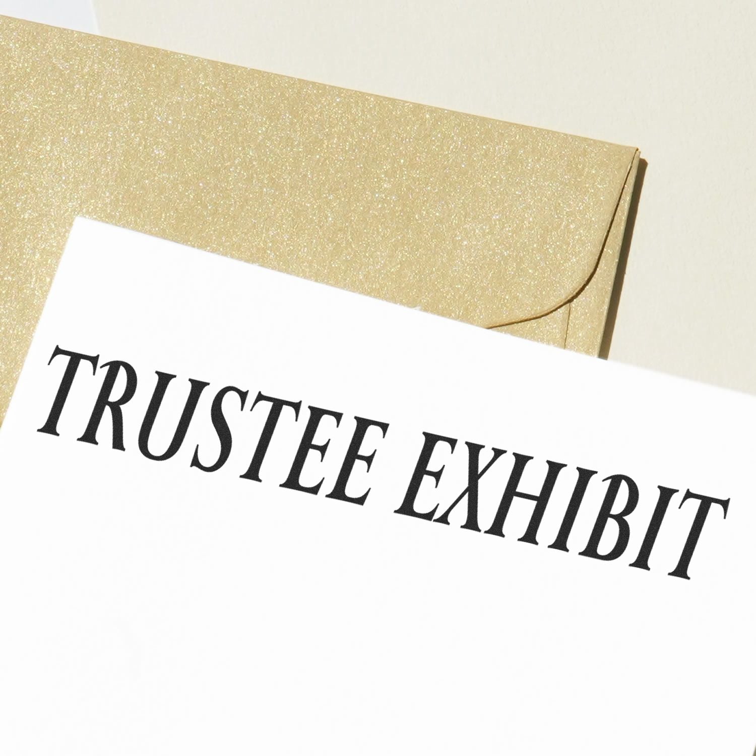 Trustee Exhibit rubber stamp impression on a white document, with a gold envelope in the background.