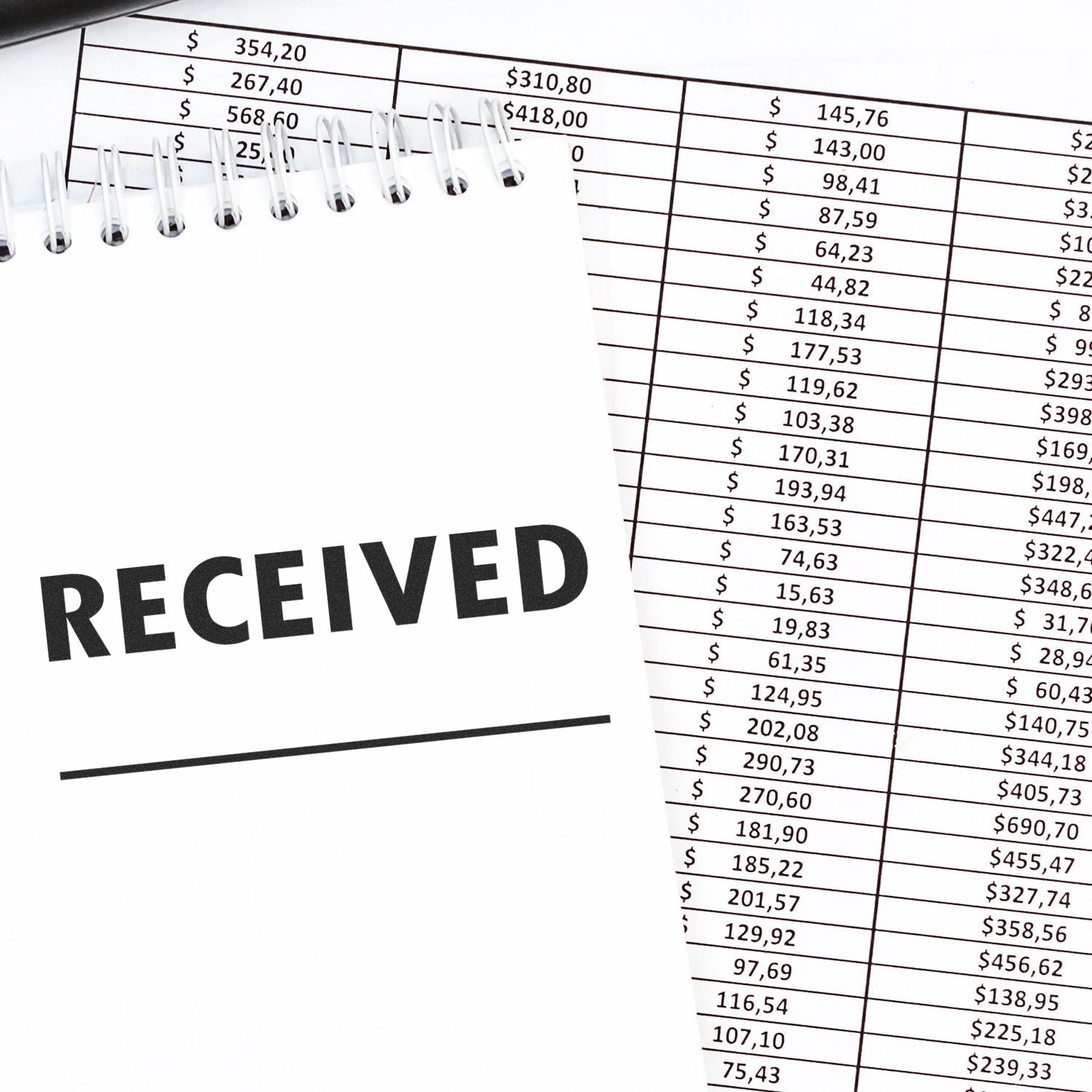 Two Line Received Rubber Stamp on a notepad next to a financial spreadsheet with various dollar amounts.