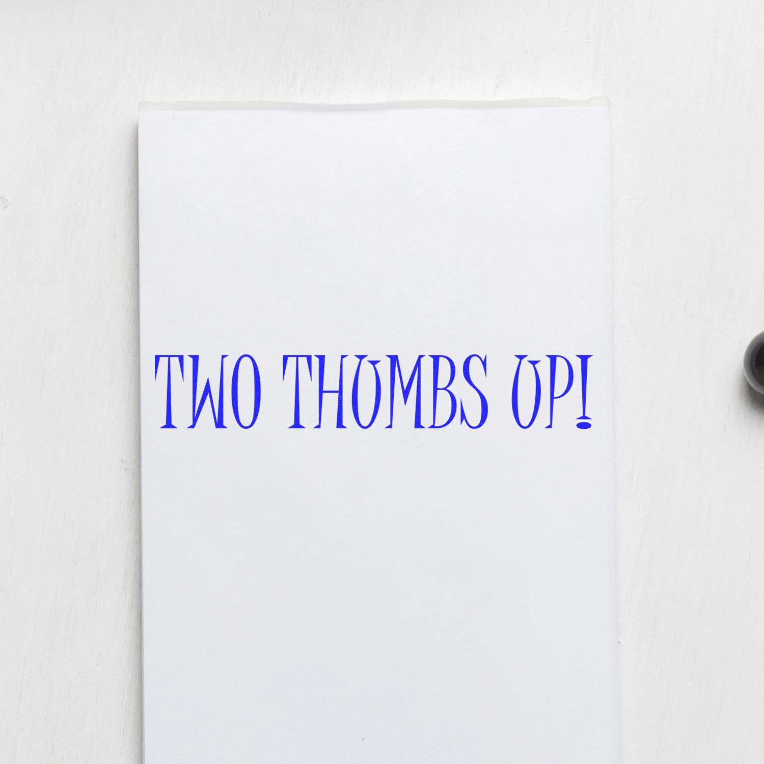 Stamped paper with 'TWO THUMBS UP!' in blue ink using the Large Self Inking Two Thumbs Up Stamp, placed on a white surface.