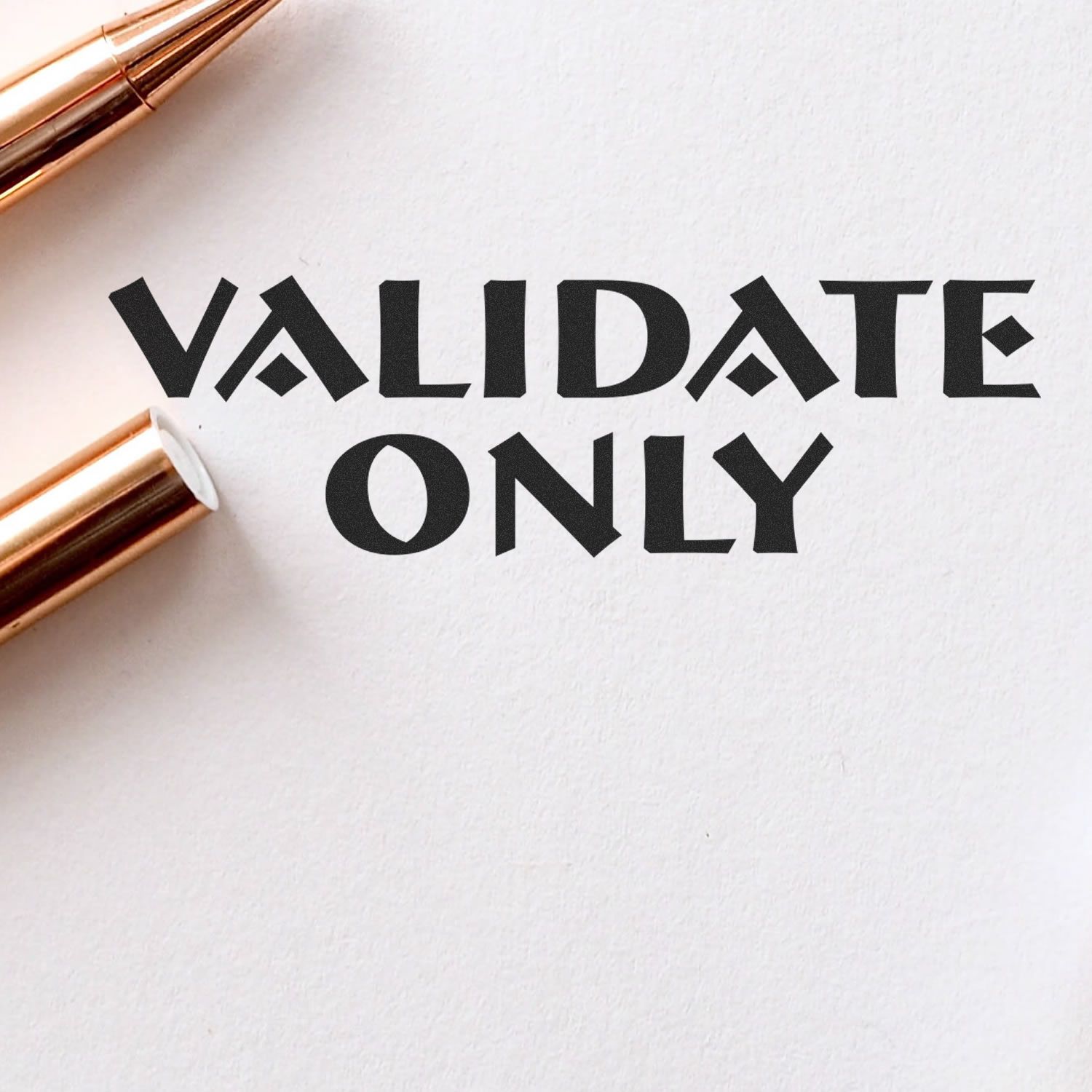 Slim Pre-Inked Validate Only Stamp imprint on white paper with two gold pens nearby.