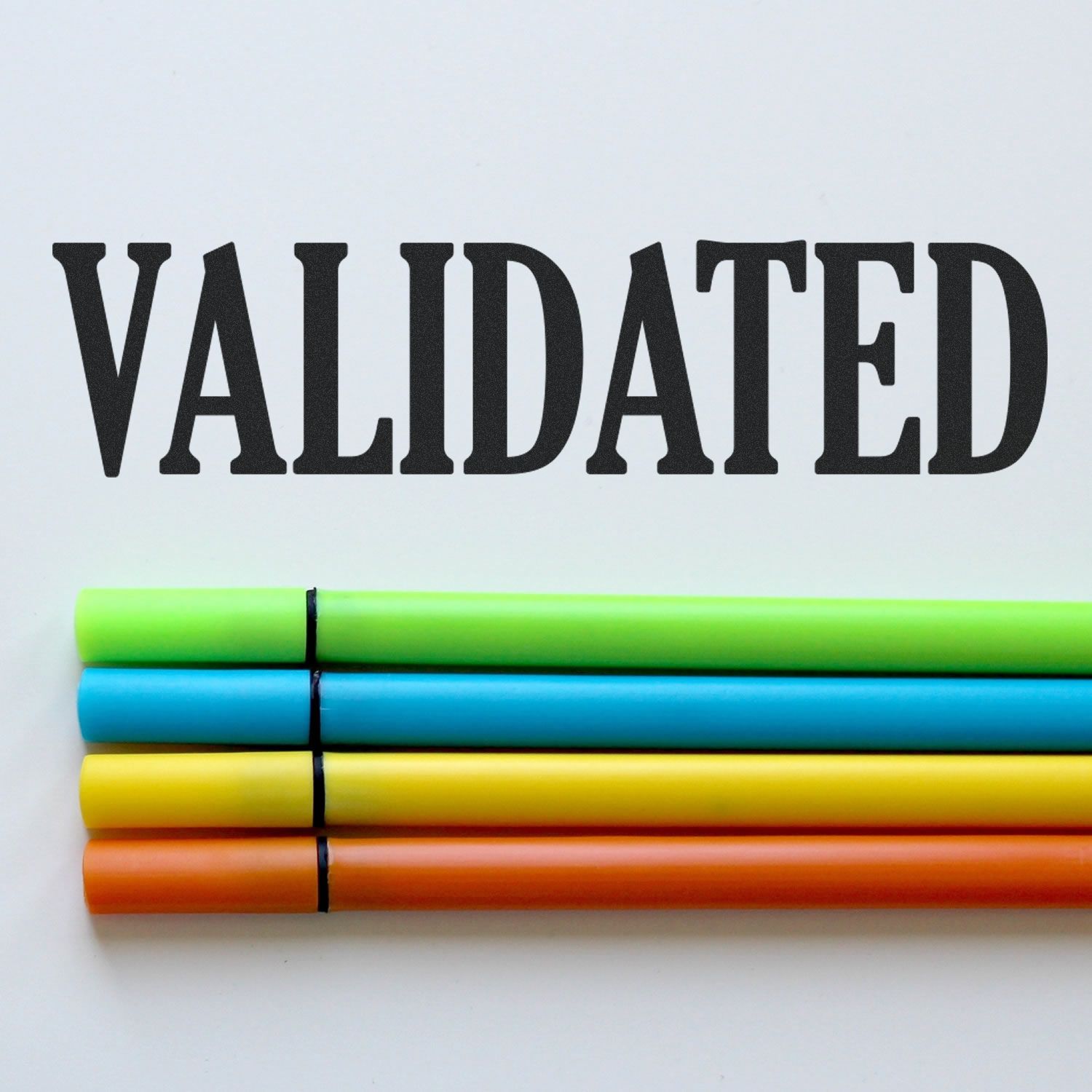 Validated rubber stamp impression above four colorful markers on a white background.